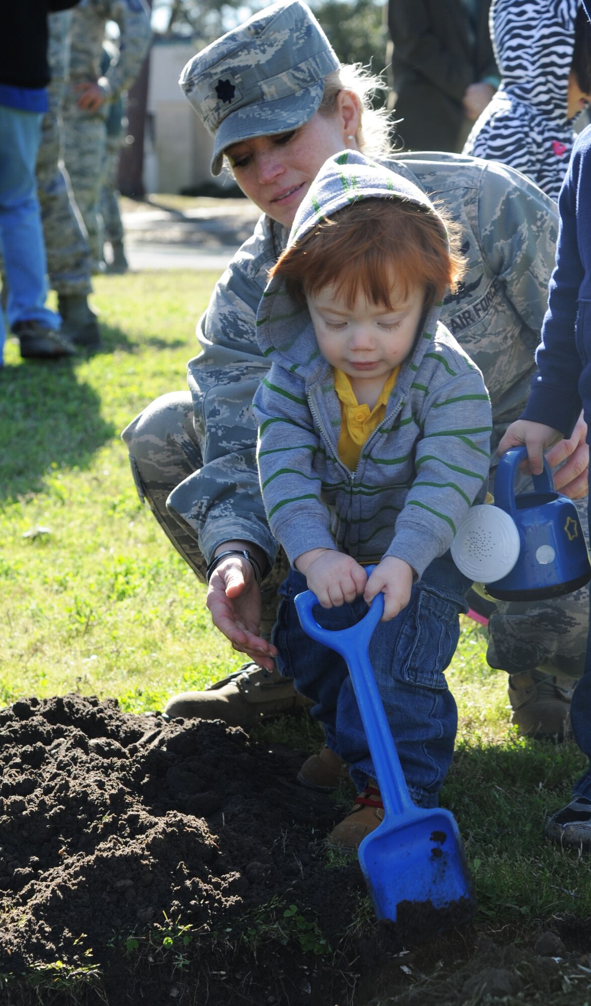 Lt. Col. Michelle Carns, 338th Training Squadron commander, assists her son with his shove during a tree-planting ceremony for Arbor Day Feb. 21, 2014, at the child development center, Keesler Air Force Base, Miss.  The award was presented to Keesler for the 21st consecutive year for its tree management program.  (U.S. Air Force photo by Kemberly Groue)
