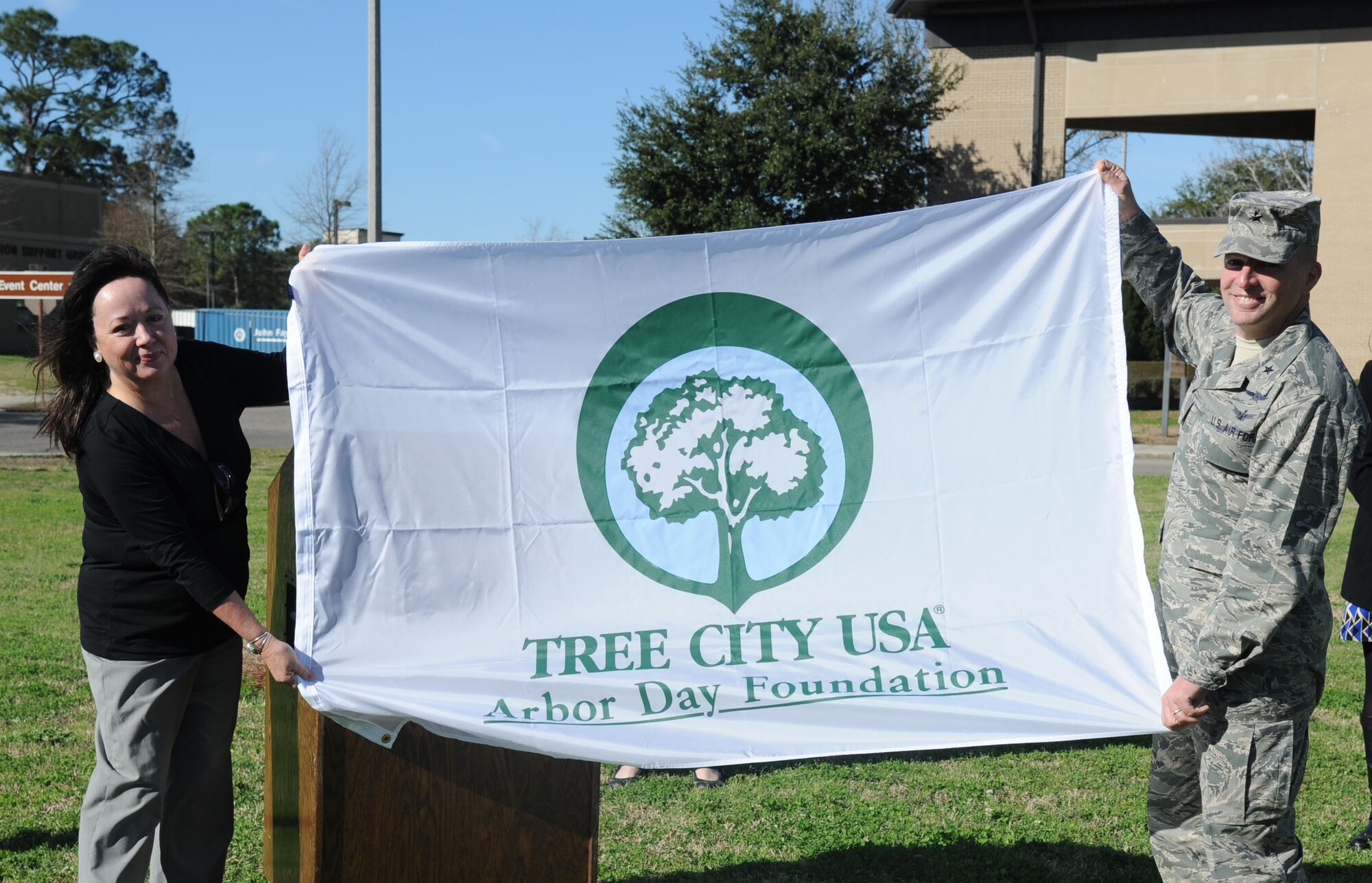 Donna Yowell, Mississippi Urban Forest Council executive director, presents the Tree City USA award to Brig. Gen. Patrick Higby, 81st Training Wing commander, during a tree-planting ceremony for Arbor Day Feb. 21, 2014, at the child development center, Keesler Air Force Base, Miss.  The award was presented to Keesler for the 21st consecutive year for its tree management program.  (U.S. Air Force photo by Kemberly Groue)