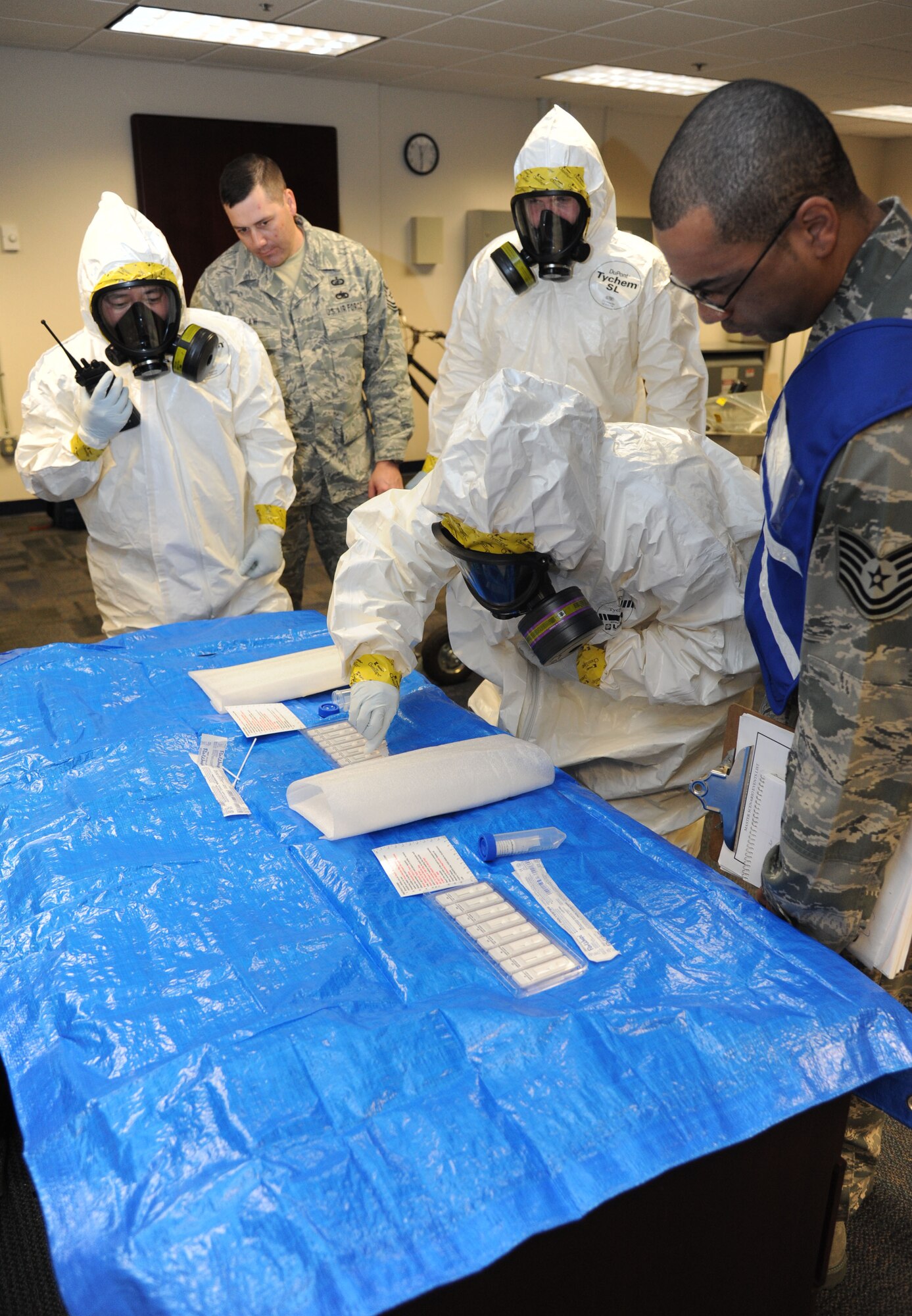 Members of the 81st Aerospace Medicine Squadron bioenvironmental team, use a biological agent identification kit to help identify hazardous solids as they are evaluated by Tech. Sgt. Chris Bowens, 81st AMDS Wing Inspection Team member, during a Chemical, Biological, Radiological, Nuclear, and high-yield Explosive exercise scenario Feb. 20, 2014, at Wolfe Hall, Keesler Air Force Base, Miss.  The exercise scenario began with a group of Airmen moving old boxes from a storage room where a box containing a bag of powder dropped, causing it to get onto several of the Airmen.  Immediately, the Airmen simulated eye irritations, runny noses, difficulty breathing and burning sensations on their hands and faces from exposure to the agent.  (U.S. Air Force photo by Kemberly Groue)