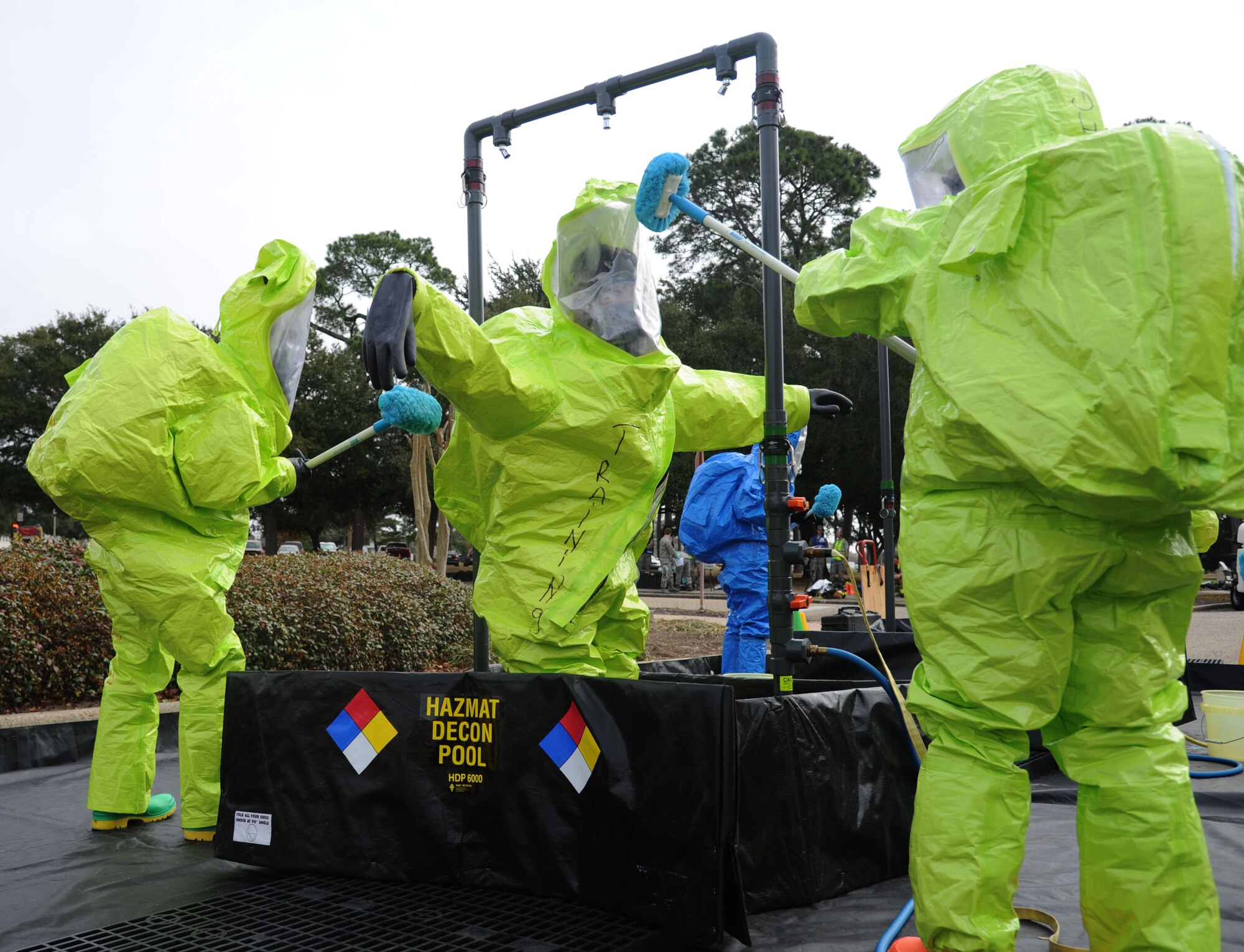 Members of the Keesler Fire Department perform decontamination procedures on a fellow firefighter after he was exposed by a biological agent during a Chemical, Biological, Radiological, Nuclear, and high-yield Explosive exercise scenario Feb. 20, 2014, near Wolfe Hall, Keesler Air Force Base, Miss.  The exercise scenario began with a group of Airmen moving old boxes from a storage room where a box containing a bag of powder dropped, causing it to get onto several of the Airmen.  Immediately, the Airmen simulated eye irritations, runny noses, difficulty breathing and burning sensations on their hands and faces from exposure to the agent.  (U.S. Air Force photo by Kemberly Groue)
