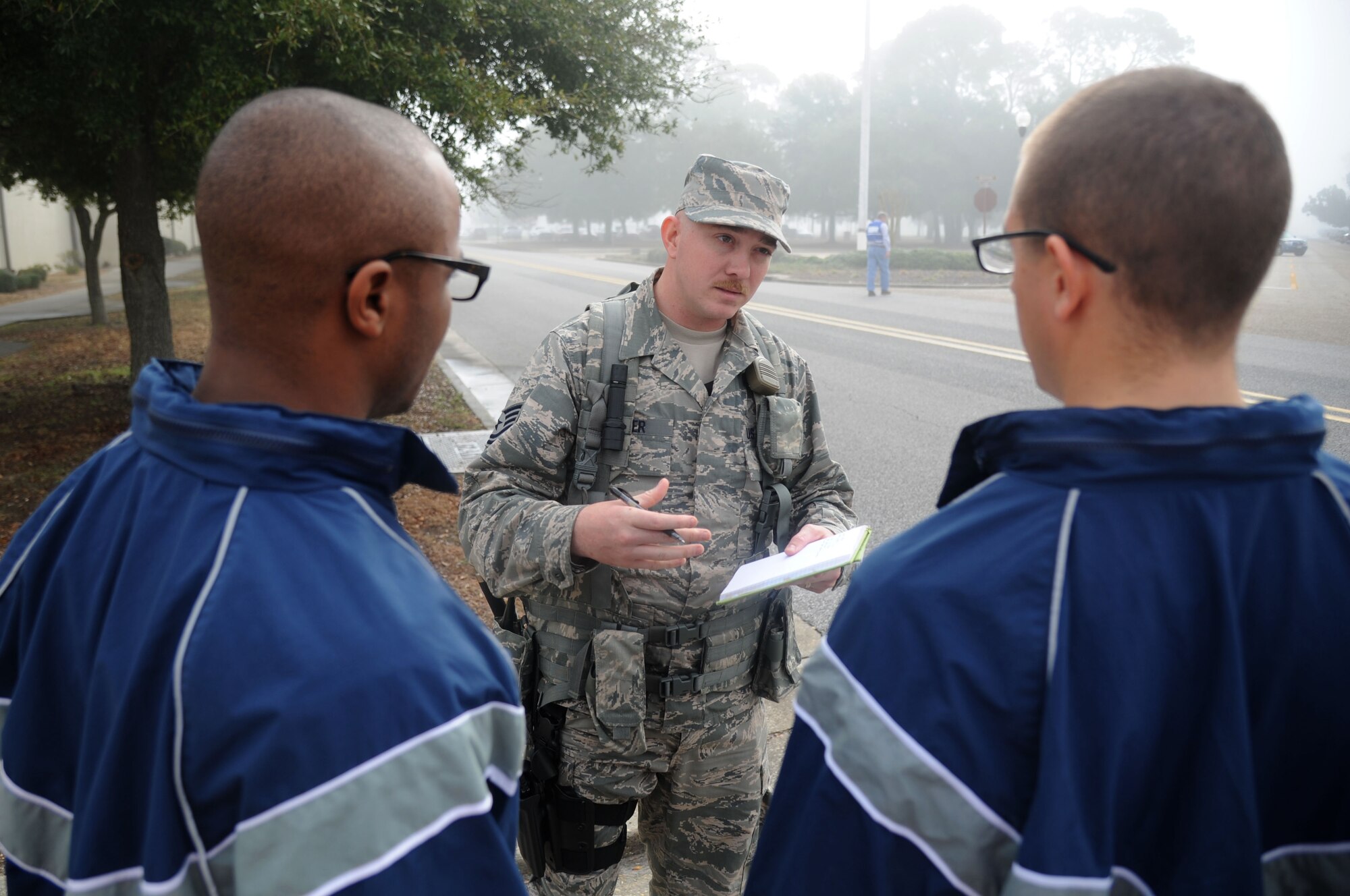 Tech. Sgt. Eric Hafner, 81st Security Forces Squadron, questions Airmen 1st Class Brian Hudson and Mark Dunton, 338th Training Squadron, during a Chemical, Biological, Radiological, Nuclear, and high-yield Explosive exercise scenario, Feb. 20, 2014, near Wolfe Hall, Keesler Air Force Base, Miss.  The exercise scenario began with a group of Airmen moving old boxes from a storage room where a box containing a bag of powder dropped, causing it to get onto several of the Airmen.  Immediately, the Airmen simulated eye irritations, runny noses, difficulty breathing and burning sensations on their hands and faces from exposure to the agent.  (U.S. Air Force photo by Kemberly Groue)