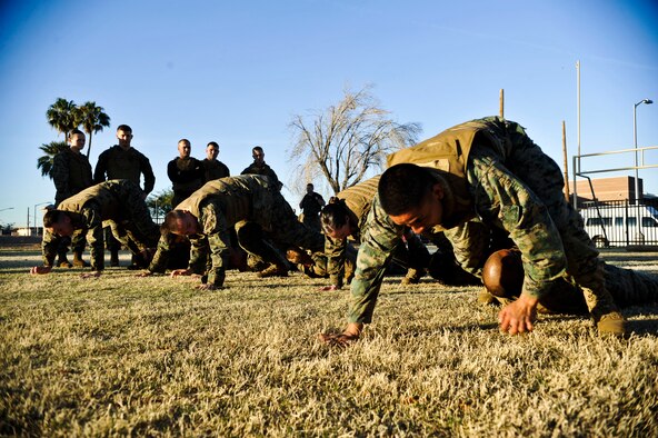 Marines from Bulk Fuel Company C perform a pistol belt drag Feb. 14 during Marine Corps Martial Arts Program instructor training course at the Luke Air Force Base soccer field. The pistol belt drag enables you and the casualty to remain low on the ground, more protected from enemy fire. (U.S. Air Force photo/Senior Airman David Owsianka)