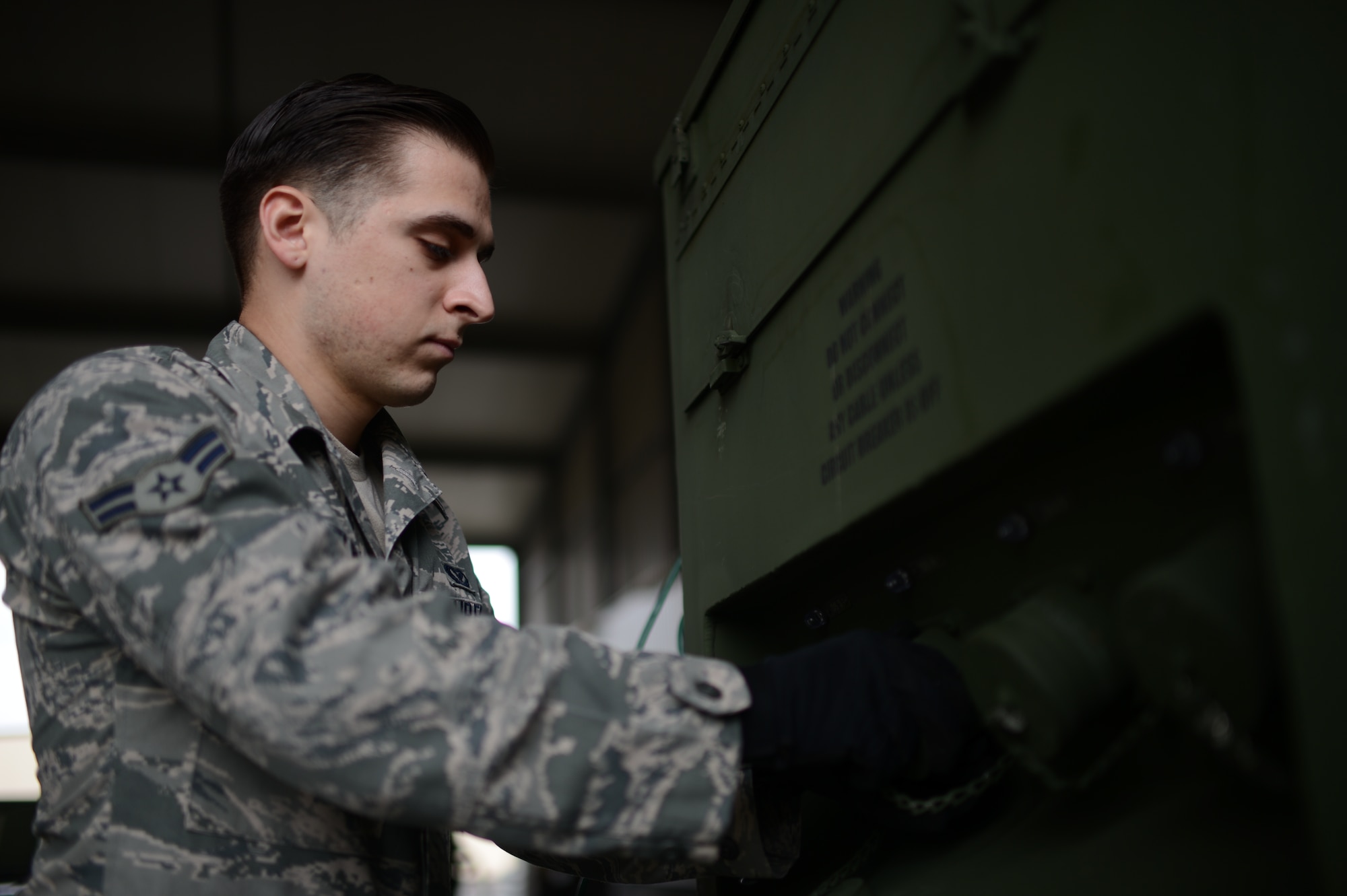 U.S. Air Force Airman 1st Class Christopher Lomelin, 606th Air Control Squadron power production technician from Caredo, Texas, removes the cap of a plug on a generator at Spangdahlem Air Base, Germany, Feb. 20, 2014. The generator can supply satellite equipment power for up to eight continuous hours on one tank of fuel. (U.S. Air Force photo by Senior Airman Gustavo Castillo/Released)