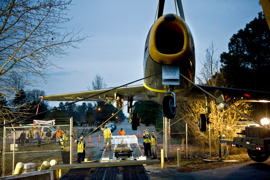 An F-86 Sabre aircraft is lifted over the perimeter gate, Feb. 20, 2014, at Seymour Johnson Air Force Base, N.C.  Airmen from the 4th Equipment Maintenance Squadron spent hours carefully hoisting and maneuvering the Sabre, which belongs to the city of Goldsboro, from one trailer to another in order to get the aircraft onto base.  Members will spend the next few months repairing and painting the aircraft to return to the city.  (U.S. Air Force photo by Airman 1st Class Brittain Crolley)