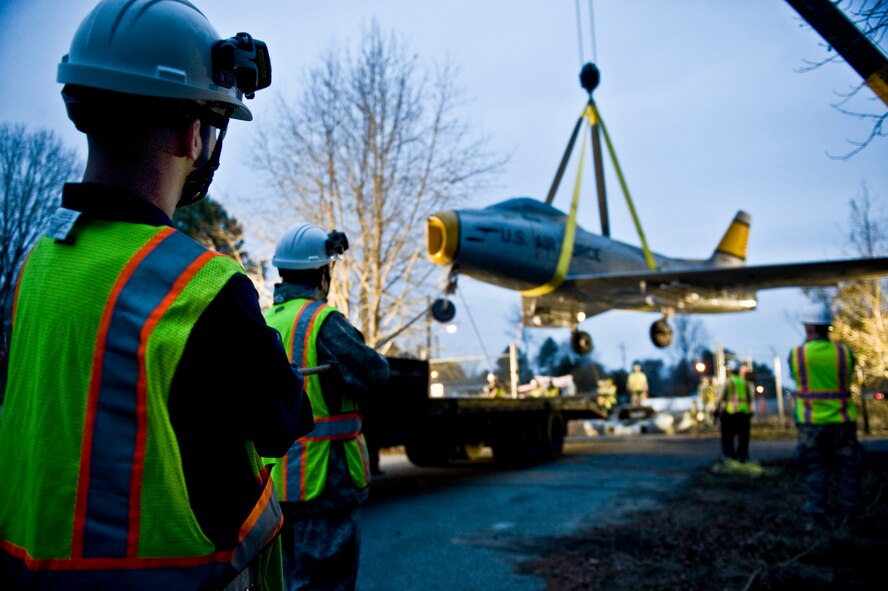 Airmen from the 4th Equipment Maintenance Squadron stabilize an F-86 Sabre aircraft as it is lifted over the perimeter gate, Feb. 20, 2014, at Seymour Johnson Air Force Base, N.C.  The Sabre was the Air Force's first swept-wing jet fighter and made its initial flight in October 1947. Airmen from the 4th EMS will restore the aircraft, which belongs to the Goldsboro Police Department, during the next few months to fix structural and cosmetic flaws. Once completed, the aircraft will be returned to the city for display. (U.S. Air Force photo by Airman 1st Class Brittain Crolley)