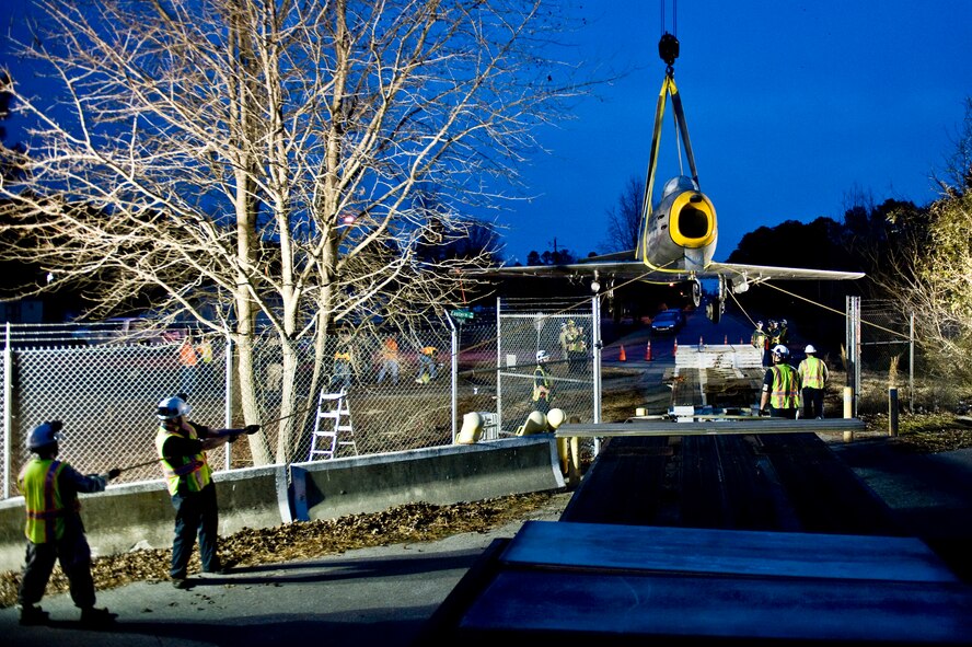 Airmen from the 4th Equipment Maintenance Squadron help stabilize and lift an F-86 Sabre aircraft over the perimeter gate, Feb. 20, 2014, at Seymour Johnson Air Force Base, N.C. The 4th Fighter Wing has a long-standing history with the Sabre, becoming the first group to fly the aircraft during the Korean War. Airmen from the 4th EMS will restore the aircraft, which belongs to the Goldsboro Police Department, during the next few months to fix structural and cosmetic flaws. Once completed, the aircraft will be returned to city for display. (U.S. Air Force photo by Airman 1st Class Brittain Crolley)