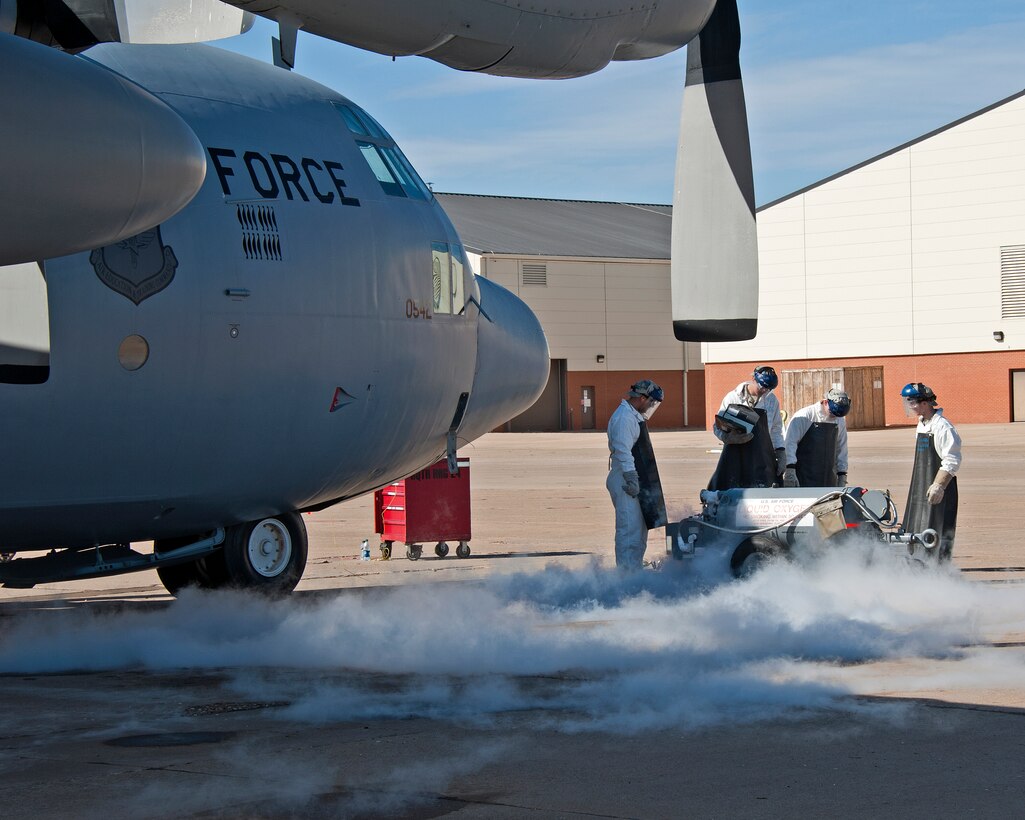 U.S. Air Force instructor Staff Sgt. Carlo Estrada, Airman Tyler Evon, John Izzy and Nicholas Preston of the 362nd Training Squadron, transfer liquid oxygen to an LOX (liquid oxygen) reservoir in a C-130 aircraft. Spewing liquid oxygen is captured by a pan underneath the valves on February 13, 2014 at Sheppard Air Force Base, Texas. (U.S. Air Force photo by Frank Carter/Released)