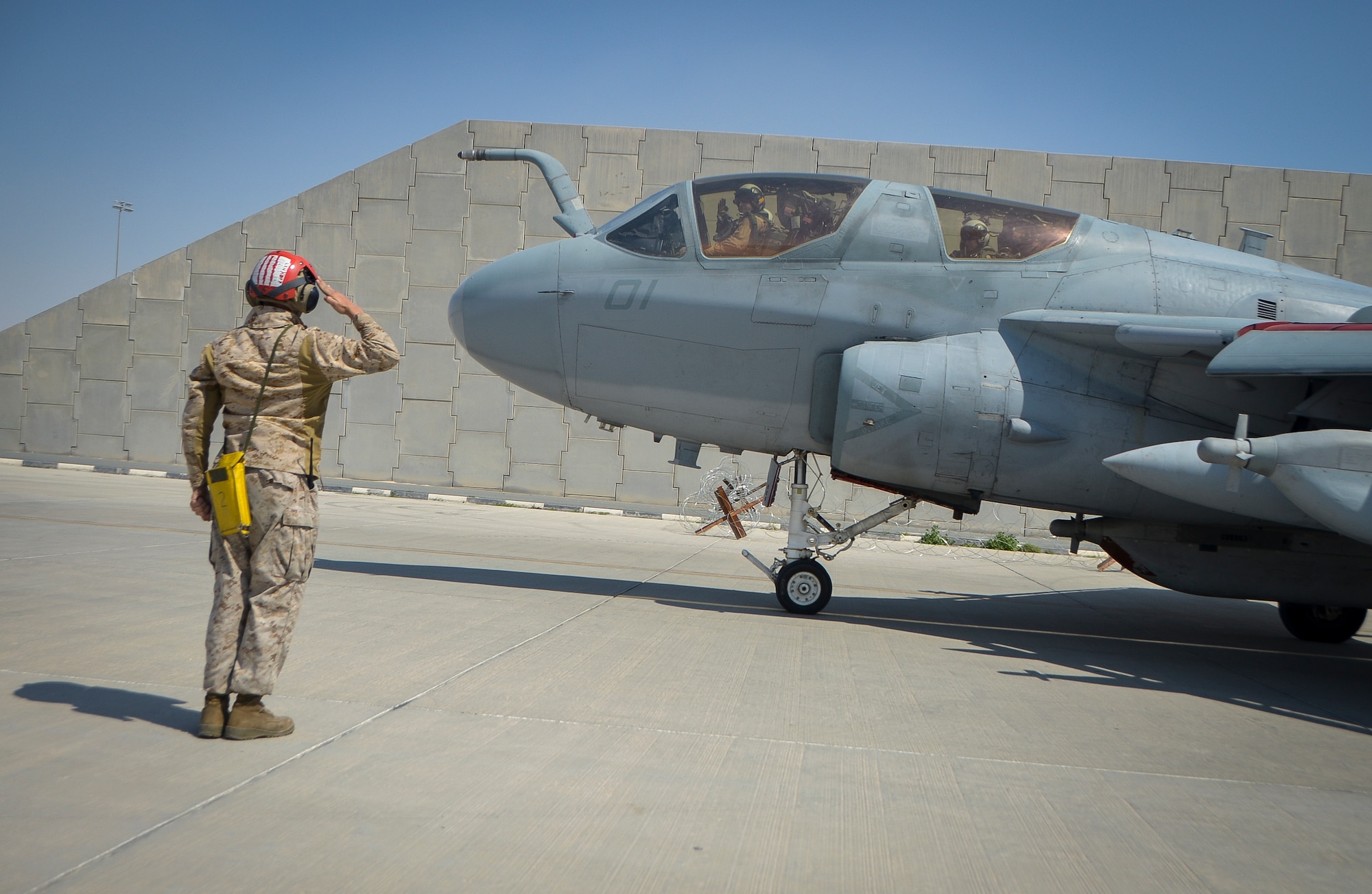 A Marine salutes the pilot of an EA-6B Prowler before take-off at Al Udeid Air Base, Qatar, Feb. 18, 2014. The Marine Tactical Electronic Warfare Squadron 3 (VMAQ-3) “Moondogs” fly Prowlers, which is a four-seat, twin-engine tactical electronic attack aircraft capable of attacking and jamming enemy radio, communications and radar operations. The Prowlers who were previously deployed to Afghanistan have been moved to AUAB and are currently being supported by more than 200 Marines from Marine Corps Air Station Cherry Point, N.C. (U.S. Air Force photo/Senior Airman Jared Trimarchi)