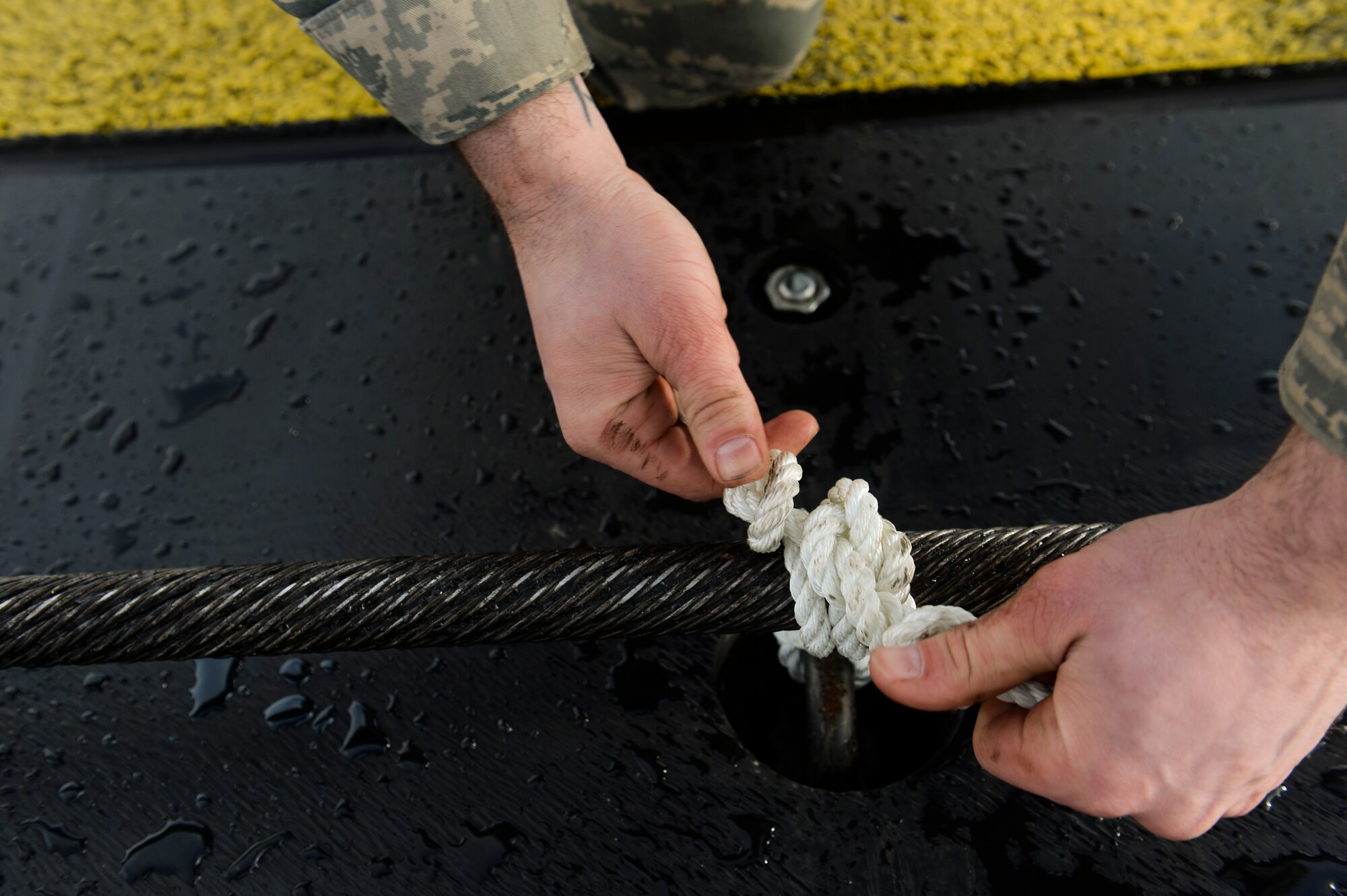 U.S. Air Force Senior Airman Matthew Wallis, a 52nd Civil Engineer Squadron electrical power production journeyman from Mackinaw City, Mich., ties down a barrier cable Feb. 21, 2014, at Spangdahlem Air Base, Germany. The barrier cables act as a last resort to stop an aircraft when there is a mechanical failure with the brakes. (U.S. Air Force photo by Senior Airman Rusty Frank/Released)