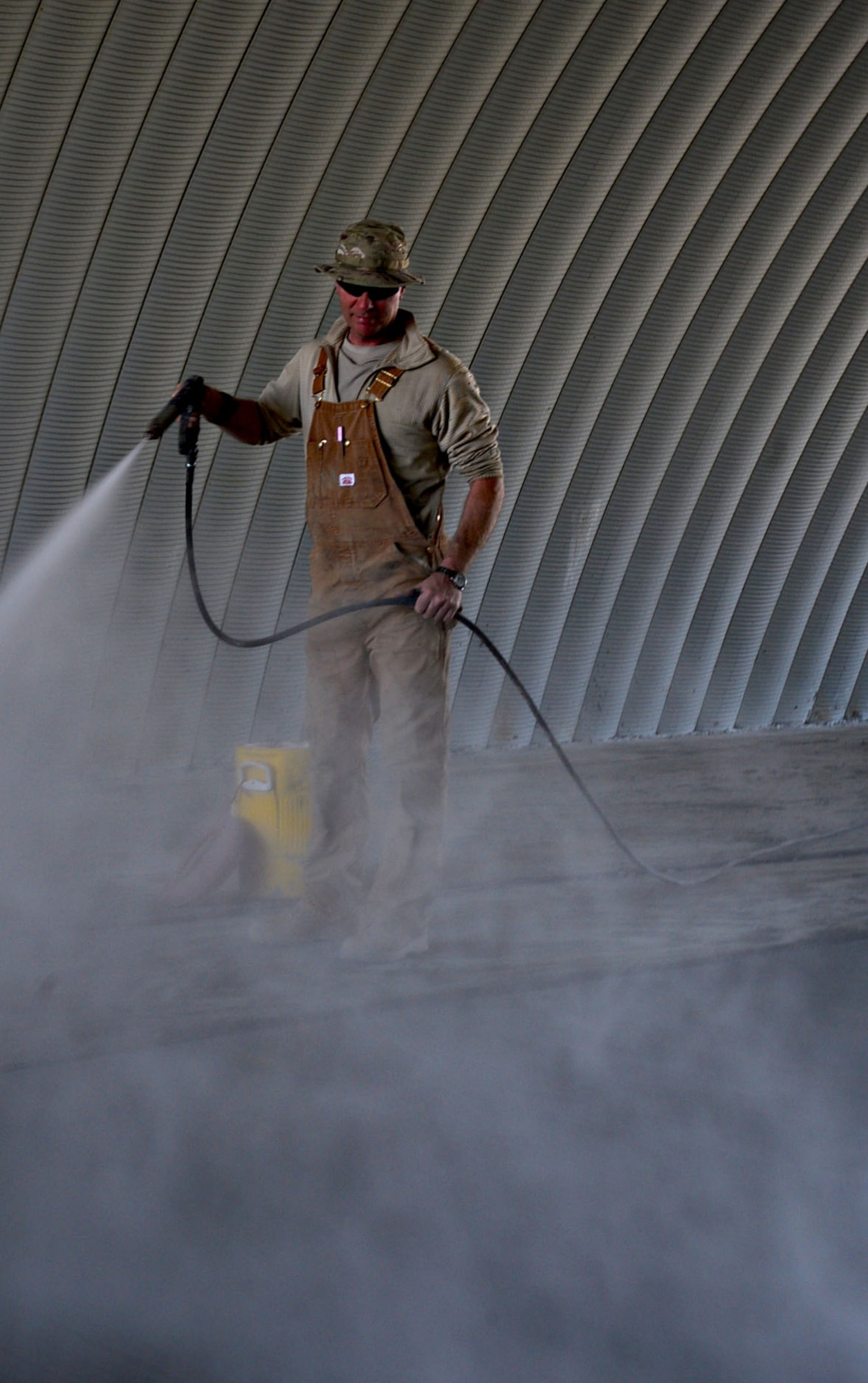 Master Sgt. Mack Lord, 557th Expeditionary Red Horse Squadron structures, hydrates a slab of curing concrete in the K-Span at an undisclosed location in Southwest Asia. The structure is replacing older, temporary facilities and will add capability and increase quality of life for the 386th Expeditionary Civil Engineer Squadron Airmen. (U.S. Air Force photo by Senior Airman Desiree W. Moye)