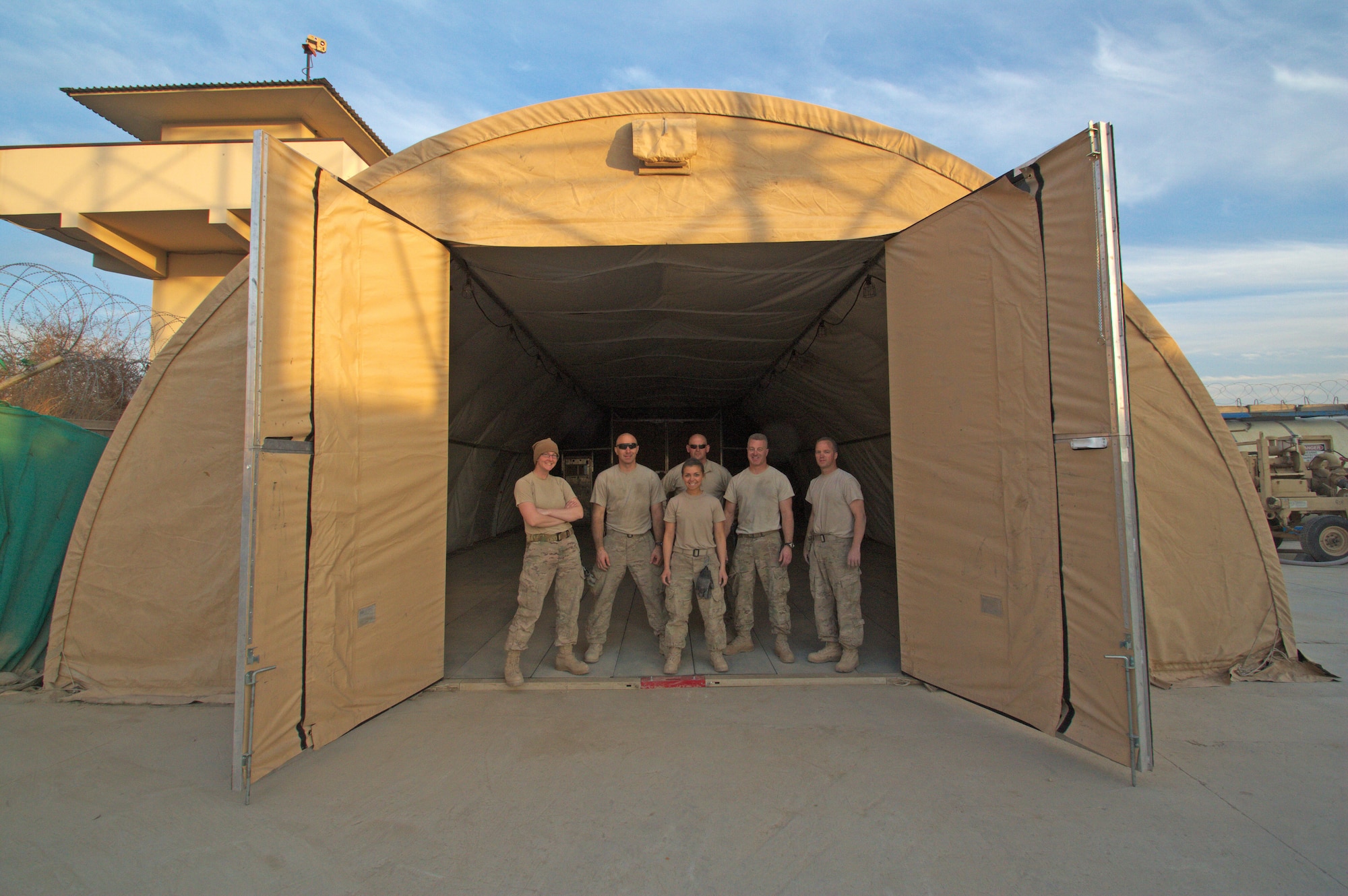 Airmen from the 451st Air Expeditionary Group stand in the entrance of an Alaska tent that they just completed erecting at Jalalabad, Afghanistan, Feb. 13, 2014. This was one of two tents built in just three days by the crew that traveled in from Kandahar, providing over 2,000 square feet of needed space to the 62nd Expeditionary Reconnaissance Squadron Detachment 1. (U.S. Air Force photo by Staff Sgt. Daniel Rivera/Released)