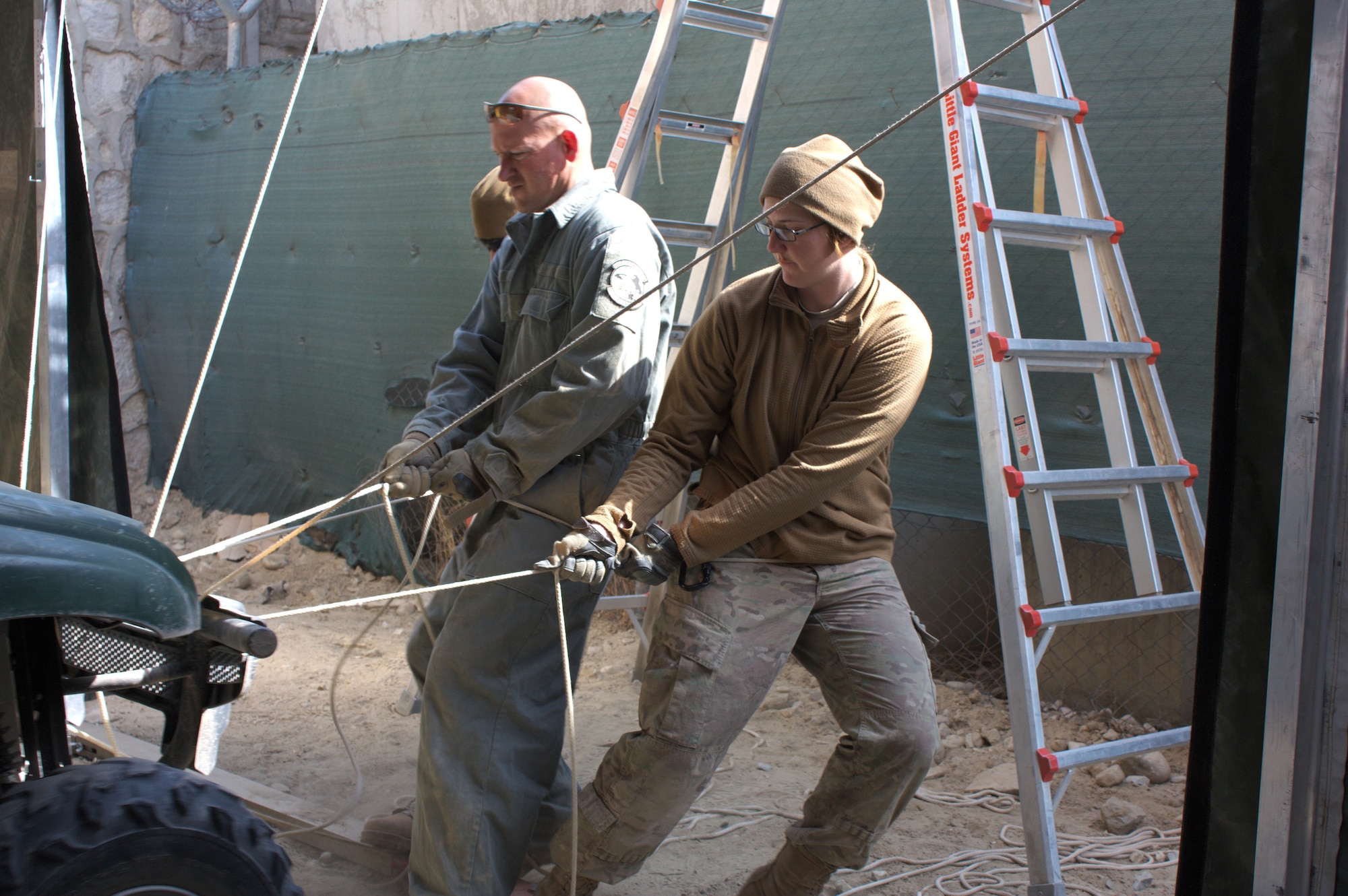 U.S. Air Force Master Sgt. Scott Kapanke and Airman 1st Class Milly Bass use ropes as leverage while trying to secure a tent liner in the new MQ-1 Combat Air Portal storage facility for the 62nd Expeditionary Reconnaissance Squadron Detachment 1, Jalalabad, Afghanistan Feb. 13, 2014. The Airmen had traveled in from Kandahar to assist with the project. (U.S. Air Force photo bySenior Airman Alexandria Bandin/ Released)