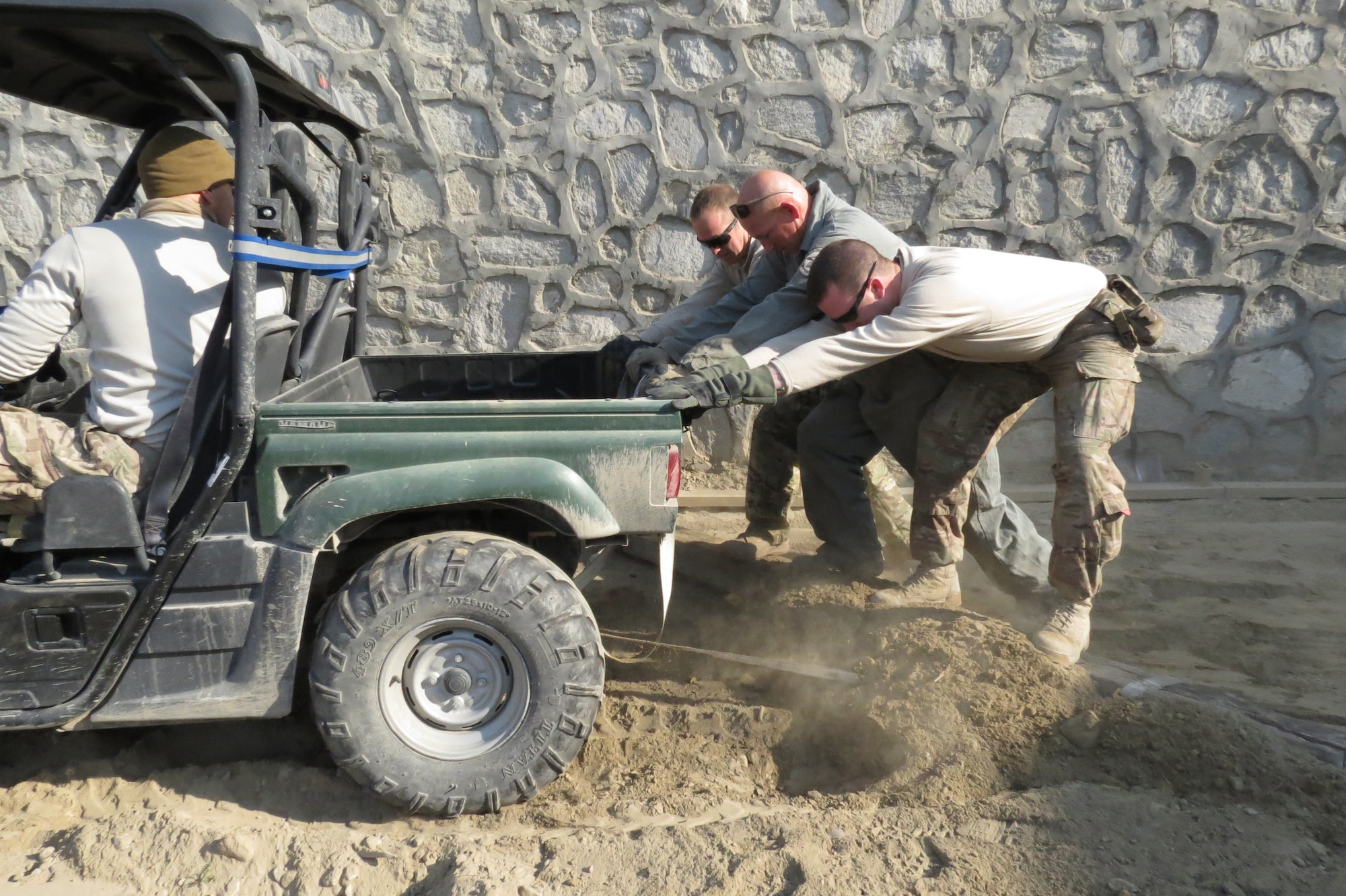 Airmen use a utility vehicle, a board and body weight to level the ground to build a new storage facility in Jalalabad, Afghanistan, Feb. 13, 2014. Due to a the lack of available means, the team resorted to many innovative techniques over the course of their week spent on the project.(U.S. Air Force photo by Senior Airman Alexandria Bandin/Released)
