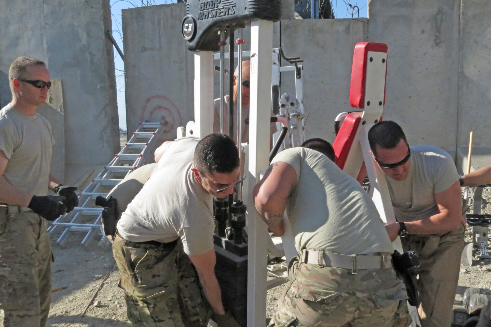 Airmen in Jalalabad, Afghanistan, come together to lend a hand while loading gym equipment into the newly built fitness center for the 62nd Expeditionary Reconnaissance Squadron Detachment 1, Feb. 12, 2014. Before the new construction, the equipment was being held in a small area that made it difficult to utilize.(U.S. Air Force photo by Senior Airman Alexandria Bandin/Released)