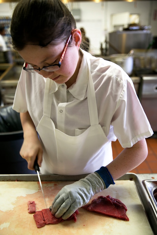 Caren-Rae Connor, 17, 12th grader in high school, slices meat at the Combat Center Officer’s Club during the 11th Annual Job Shadowing Event, Feb. 19, 2014. During the event, students were separated into their job interest fields. At the end of the day, all students met back up to enjoy a meal at the Phelps Mess Hall to discuss their experiences with each other. (Official Marine Corps Photo By Lance Cpl. Kasey Peacock/Released)