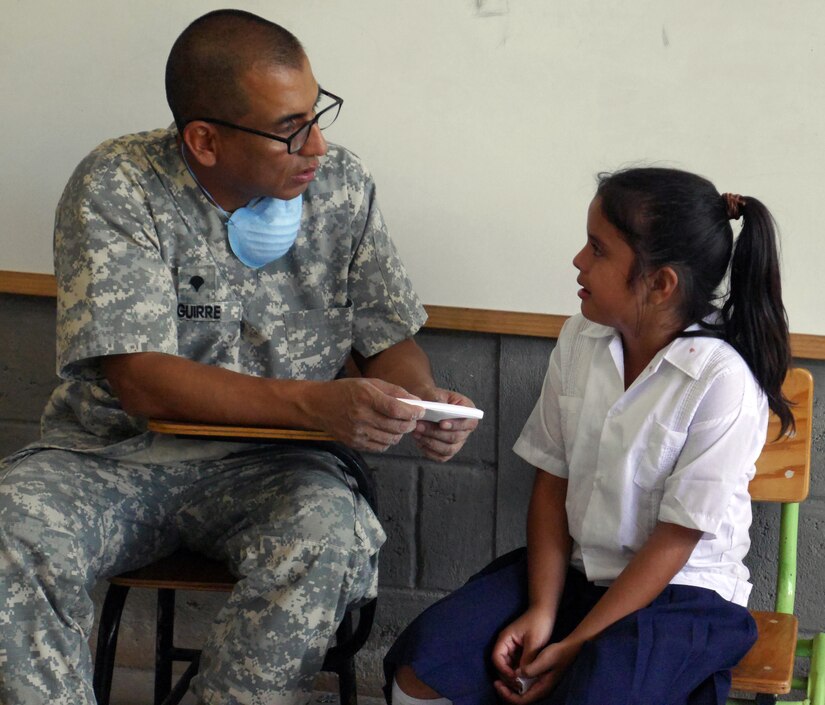 U.S. Army Spc. Harold Aguirre comforts a young Honduran child after a dental procedure during a Medical Readiness Training Exercise (MEDRETE) conducted by Joint Task Force-Bravo's Medical Element (MEDEL) in the village of Kele Kele, Department of Puerto Cortes, Honduras, Feb. 26, 2014.  MEDEL, with support from JTF-Bravo Joint Security Forces, Army Forces Battalion, and the 1-228th Aviation Regiment, partnered with the Honduran Ministry of Health, the Honduran Red Cross, and the Honduran military to provide medical care to more than 1,100 people over two days in Kele Kele and Caoba, two remote villages in the Puerto Cortes region of Honduras.  (Photo by U.S. Army Sgt. Courtney Kreft)