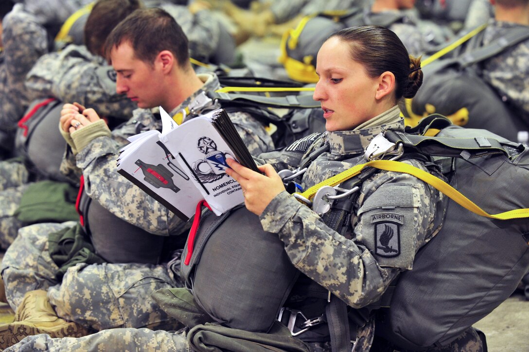 U.S. Army Capt. Lindsey Ryan sits in full harness while reading a training manual before an airborne operation at the 7th Army Joint Multinational Training Command's Grafenwoehr Training Area, Germany, Feb. 20, 2014. Ryan is a paratrooper assigned to the 173rd Brigade Support Battalion, 173rd Infantry Brigade Combat Team (Airborne).