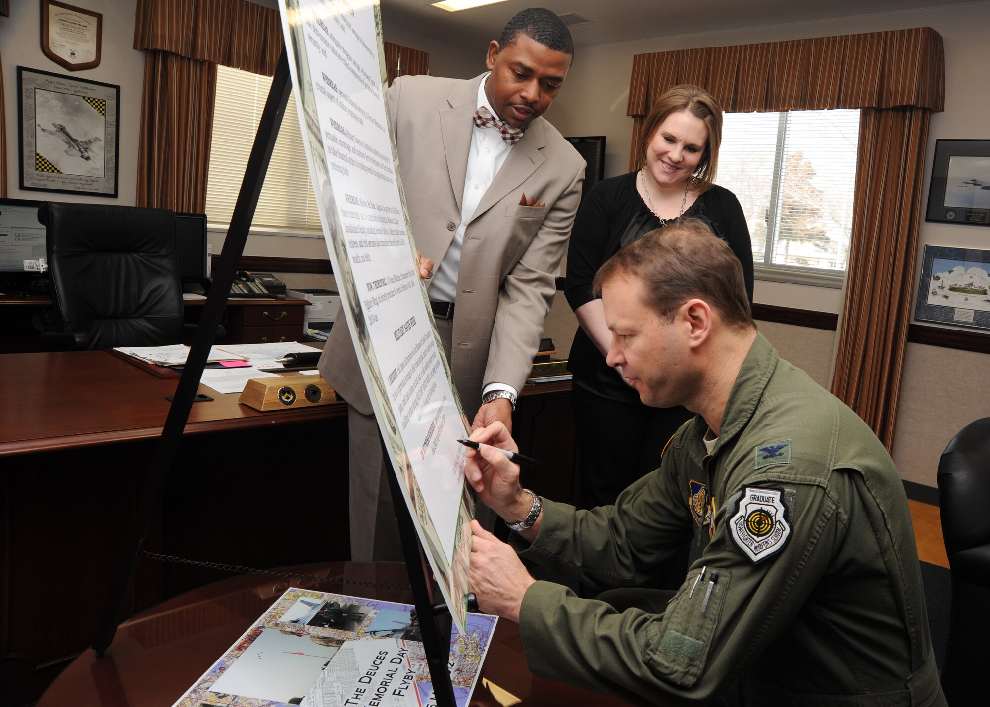 Col. Stephen Williams, 35th Fighter Wing commander, signs the 2014 Military Saves Week proclamtion Feb. 25, 2014 at Misawa Air Base, while Walter Anderson and Kari Yadao, Airman and Family Readiness Center community readiness consultant and specialist, look on. The Military Saves campaign provides an opportunity for leaders at all levels to promote and reinforce healthy financial habits for service members and their family members by creating an awareness of the importance in saving to help them reach their financial and personal goals. (U.S. Air Force photo/Staff Sgt. Alyssa C. Wallace)