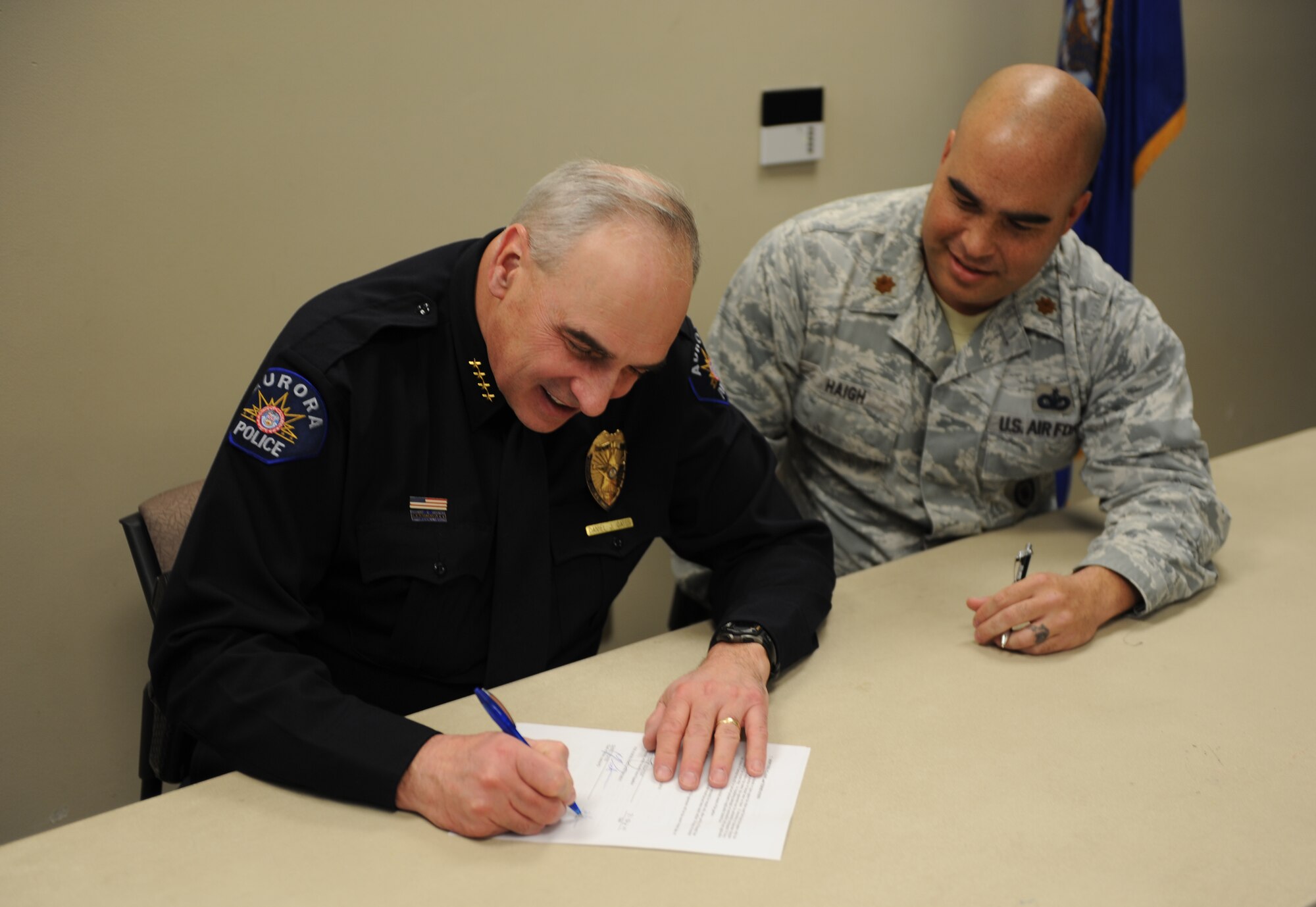 Chief Daniel Oates, Aurora Police Department, and Maj. David Haigh, 460th Security Forces Squadron commander, sign the memorandum of agreement Feb. 21, 2014, at the chapel Fellowship Hall on Buckley Air Force Base, Colo. The MOA is an arrangement between Buckley Air Force Base and the Aurora Police Department to fund a joint shooting range off base. This is just one of numerous actions taken toward the Public-Public & Public-Private, or P4, initiative. (U.S. Air Force photo by Airman Emily E. Amyotte/Released)