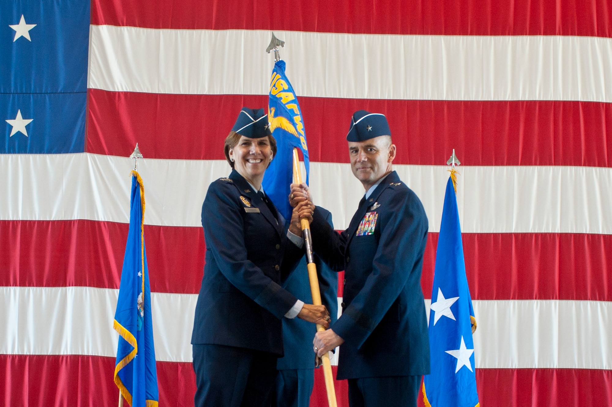 U.S. Air Force Lt. Gen. Lori Robinson, Air Combat Command vice commander, passes the guidon to Brig. Gen. Jay Silveria U.S. Air Force Warfare Center incoming commander Feb. 21, 2014, at Nellis Air Force Base, Nev. The USAFWC maximizes testing, tactics, and training to enhance total force integration of air, space and cyberspace. (U.S. Air Force photo by Senior Airman Matthew Lancaster)
