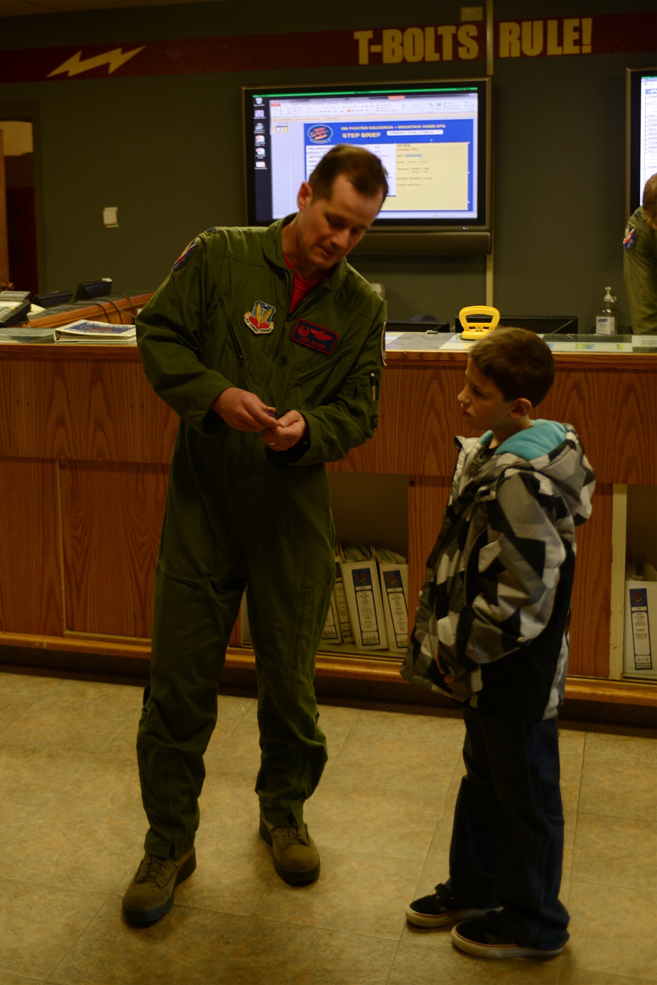 Lt. Col. Joel Myers, 389th Fighter Squadron commander, presents a squadron coin to Ryan Trick inside the 389th FS “T-Bolts” building Feb. 21, 2014, at Mountain Home Air Force Base, Idaho. Trick, who suffers from a rare form of brain cancer, visited the base with his family as an honorary member of the squadron. As an honorary T-Bolt, Trick now has a coin carried only by members of the squadron. (U.S. Air Force photo by Senior Airman Benjamin Sutton/Released)  