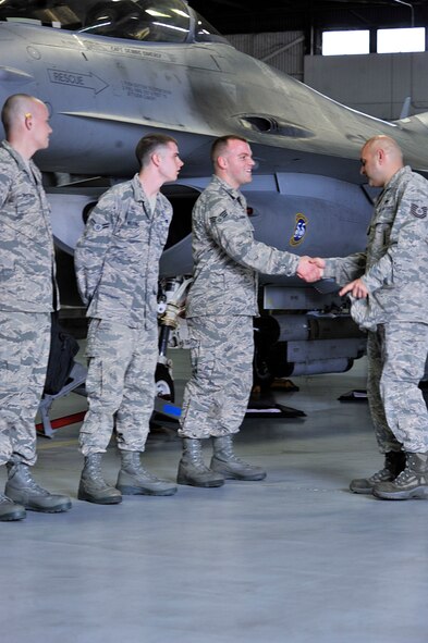 U.S. Air Force Senior Airman Tyler Daugherty, 77th Fighter Squadron load crew member shakes the hand of Tech. Sgt. Ramon Quezada, 77th Fighter Squadron weapons expeditor, after completing a load crew of the quarter competition, Shaw Air Force Base, S.C., Feb. 21, 2014. Daugherty along with Airman 1st Class Chris Wilfong and Staff Sgt. Kevin Pittman, both 77th FS load crew members, raced against the clock to load an AIM-9 missile as well as a GBU-31 joint direct attack munition. (U.S. Air Force photo by Airman 1st Class Jensen Stidham/Released) 