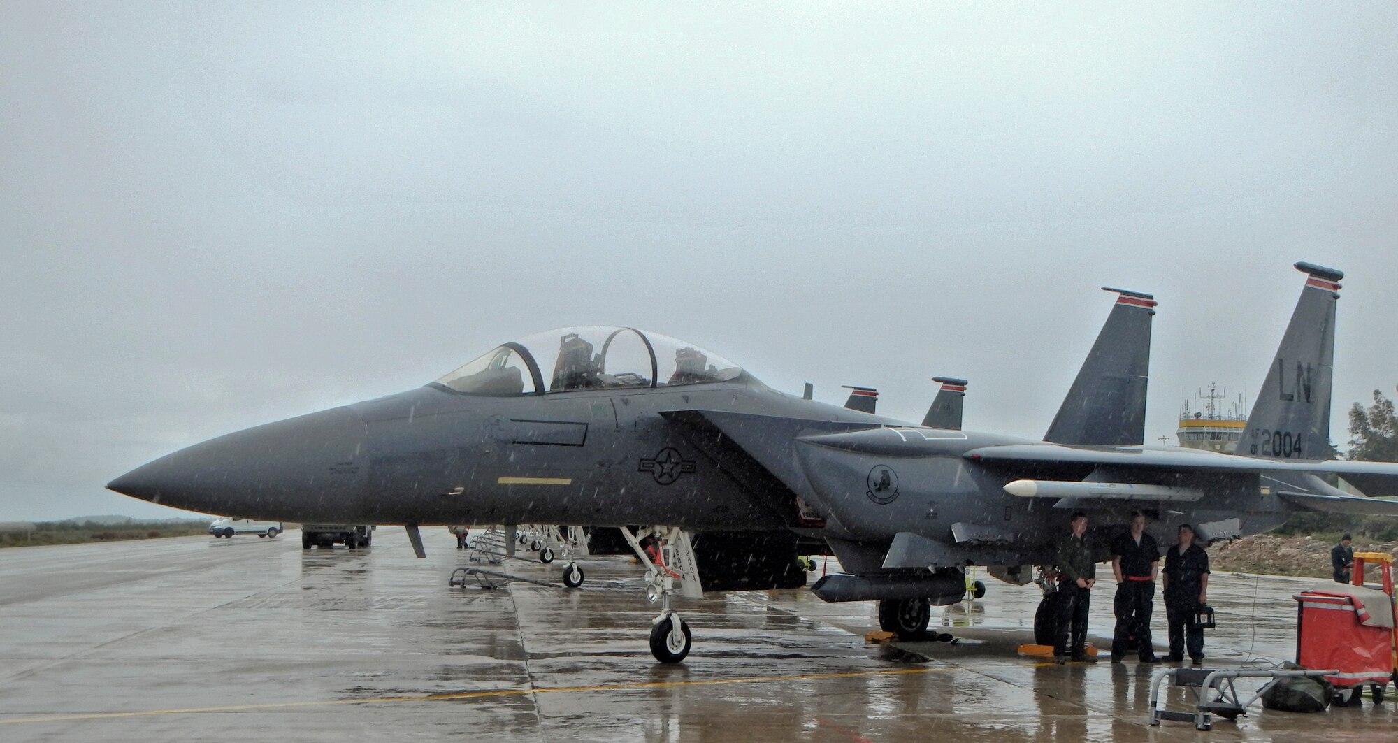 Airmen deployed to Souda Bay, Greece, with the 494th Expeditionary Fighter Squadron take shelter from a Mediterranean rain storm under an F-15E Strike Eagle Feb. 24, 2014. The 494th EFS was deployed by the 48th Fighter Wing at Royal Air Force Lakenheath, England, as one U.S. Air Forces in Europe unit participating in a flying training deployment with the Hellenic Air Force to help identify and negate coordination issues that may arise during combined NATO operations. (U.S. Air Force photo by Staff Sgt. Thomas Trower/Released)