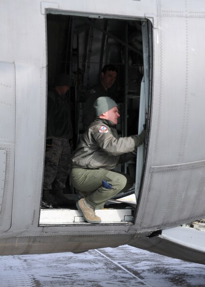 A member of the Wyoming Air National Guard manually opens the cargo door of a C-130 to unload a truck in preparation for aerial port training Feb. 8, 2014 at the 120th Fighter Wing.  National Guard photo/2nd Lt. Robin Jirovsky.