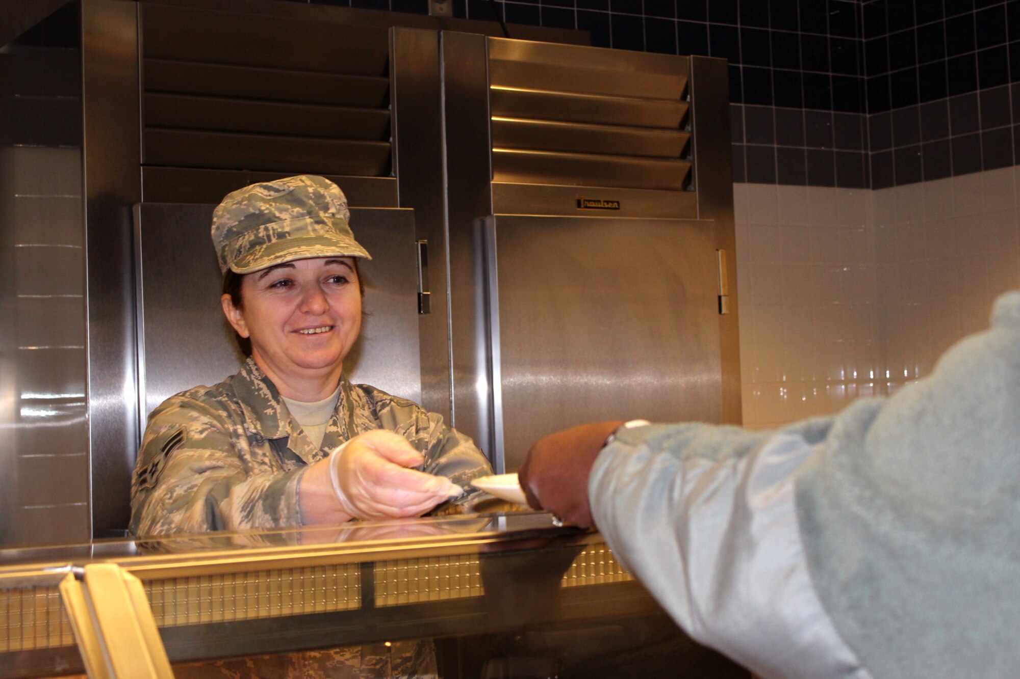 140208-Z-VA676-079 -- Airman 1st Class Elvira Shani serves an Airman during lunch at the Dining Facility at Selfridge Air National Guard Base, Mich., Feb. 8, 2014. Shani, a native of Albania, joined the Air National Guard on the day before her 40th birthday – the last day she was eligible to join – as a way to say thank you to America for the opportunities she has found since to immigrated to the U.S. about 10 years ago. (U.S. Air National Guard photo by TSgt. Dan Heaton / Released)