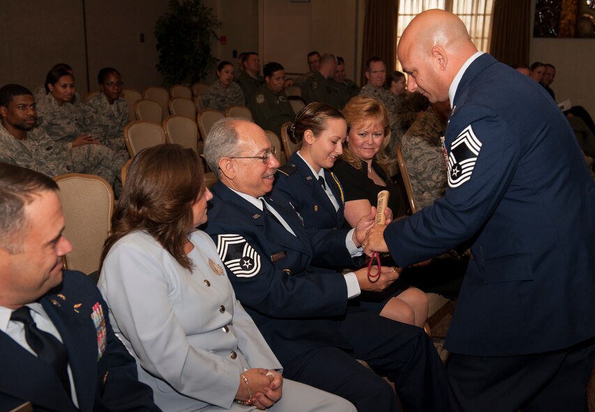 Chief Master Sgt. Jason P. Colon, 91st Operations Group superintendent, hands his father, retired Chief Master Sgt. Peter Colon, a “Bully Stick” at his promotion ceremony at Minot Air Force Base, Oct. 31, 2013. The Colons are included of a miniscule percentage of second generation chiefs. (U.S. Air Force photo/Airman 1st Class Apryl Hall)