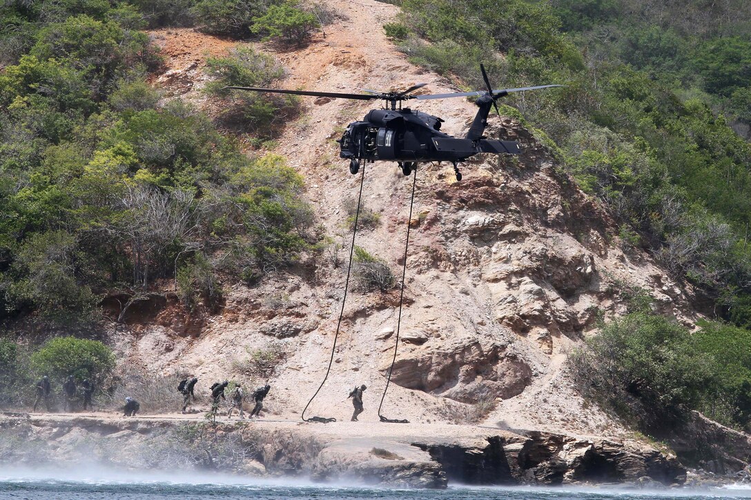 A U.S. UH-60 Black Hawk helicopter hovers over members of U.S. 7th Special Forces Group and Trinidad and Tobago defense force as they prepare to fast rope off Chacachacare Island, the western-most island off Trinidad, Feb. 14, 2014.