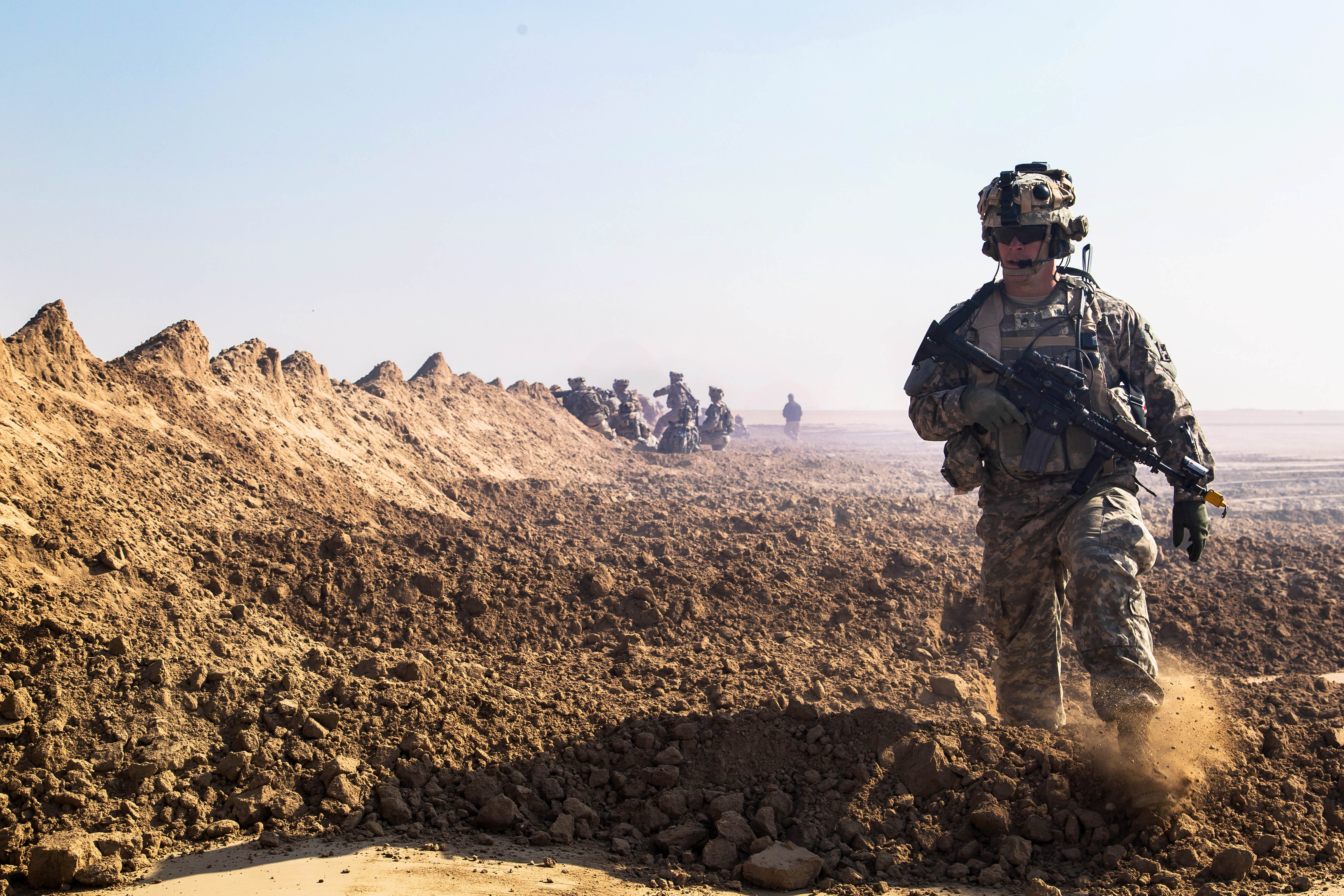 A U.s. Soldier Moves Down The Line Behind A Berm While Other Soldiers  Assault A Mock