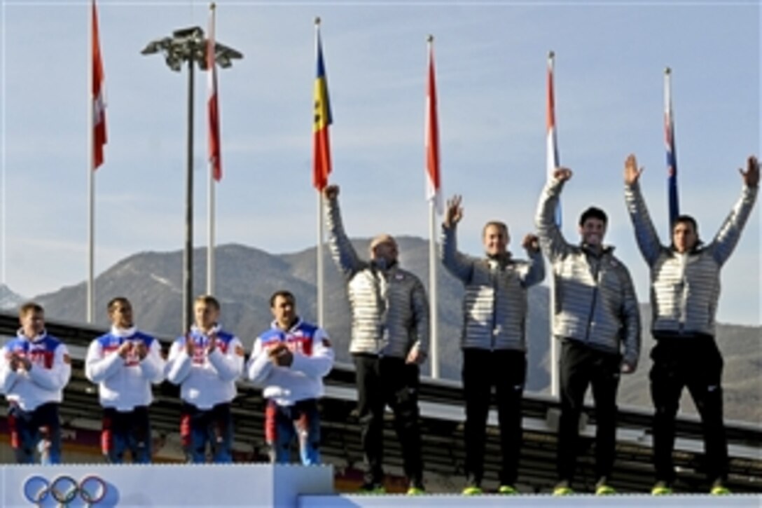Sochi 2014 Olympic Winter Games four-man bobsled gold medalists from Russia watch Team USA step onto the podium to receive their bronze medals at Sanki Sliding Centre in Krasnaya Polyana, Russia. Feb. 23, 2014. From far right to left: U.S. Army Capt. Chris Fogt of the U.S. Army World Class Athlete Program, Steve Langton, Curt Tomasevicz and former Army program bobsledder Steven Holcomb stand during the ceremony.