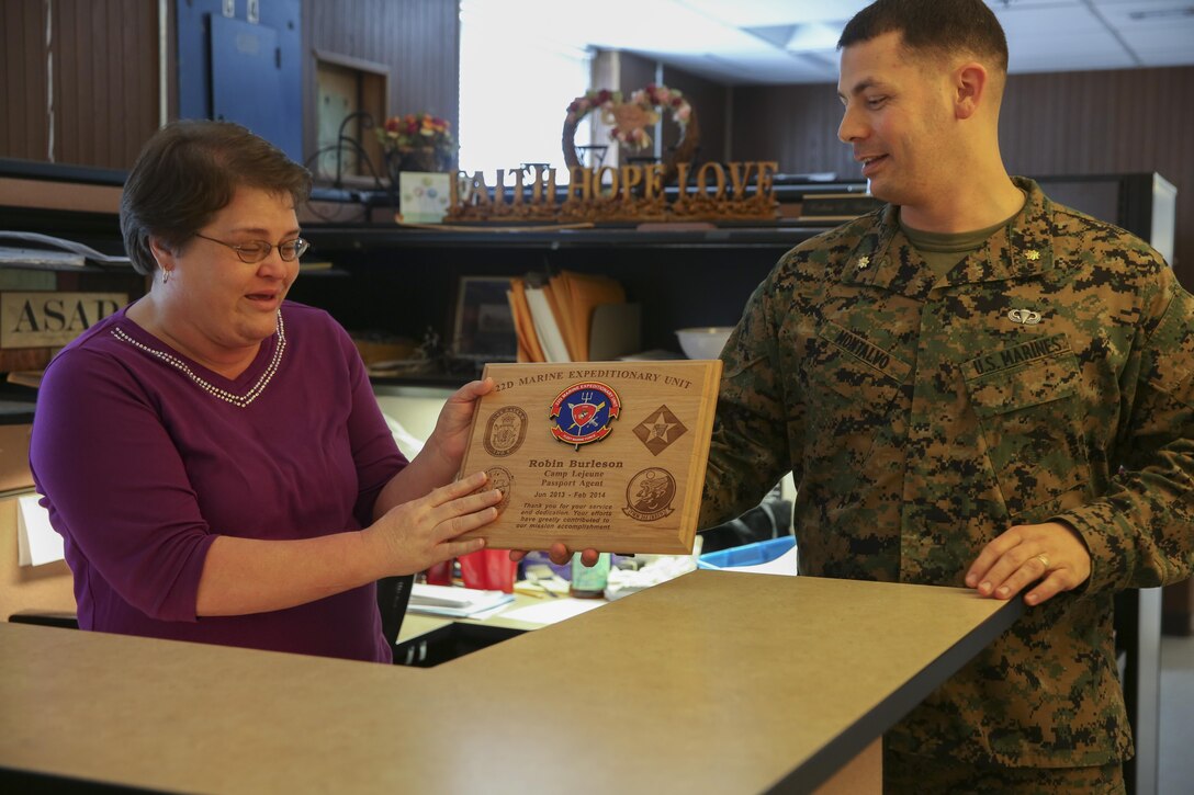 U.S. Marine Corps Maj. Eric Montalvo, 22nd Marine Expeditionary Unit (MEU) staff judge advocate, presents Robin Burleson, base passport agent, with a plaque for her support to the 22nd MEU before its deployment at Marine Corps Base Camp Lejeune, N.C., Feb. 5, 2014.The MEU deployed Feb. 7 to the U.S. 5th and 6th Fleet areas of responsibility with the Bataan Amphibious Ready Group as a sea-based, expeditionary crisis response force capable of conducting amphibious missions across the full range of military operations. (U.S. Marine Corps photo by Cpl. Manuel A. Estrada/Released)