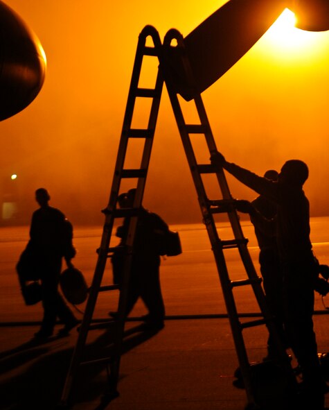 A flight crew crosses the flightline as maintenance Airmen work on a MC-130H Combat Talon II on Hurlburt Field, Fla., Feb. 19, 2014. (U.S. Air Force photo/Senior Airman Michelle Vickers)