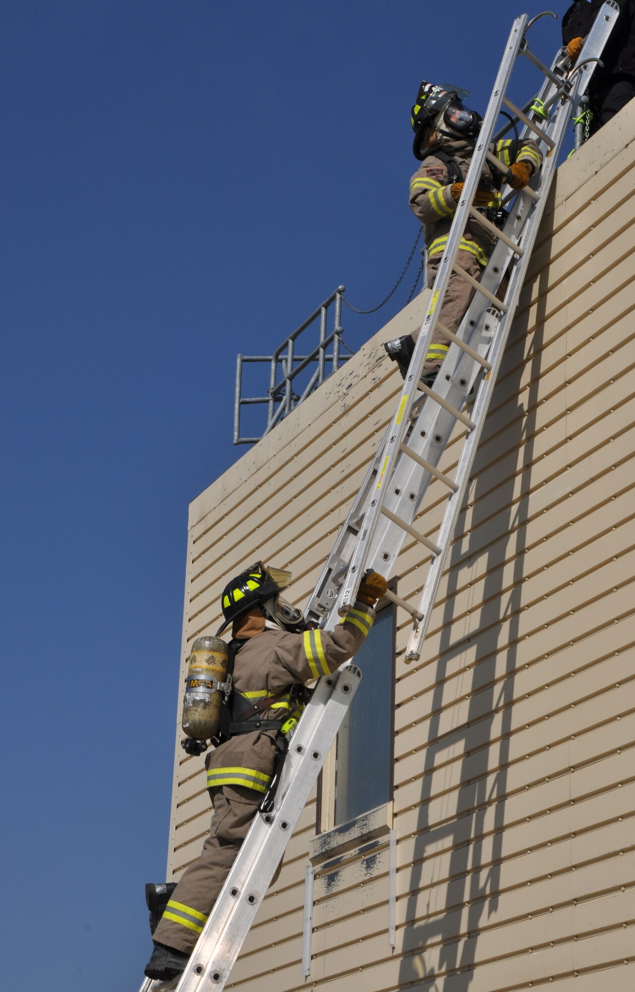 GOODFELLOW AIR FORCE BASE, Texas – Chris Little, San Angelo Fire Department recruit, hands Ethan Sedden, SAFD recruit, a ladder during tactical ventilation training at the Louis F. Garland DOD Fire Academy here Feb. 19. Firefighters use ladders to protect against slips and falls. (U.S. Air Force photo/ Senior Airman Joshua Edwards)