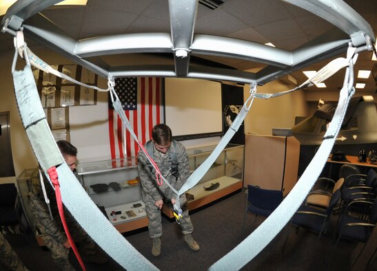 Airman 1st Class Adam Clapp, 509th Operations Support Squadron aircrew flight equipment technician, demonstrates hanging harness training at Whiteman Air Force Base Mo., Feb. 12, 2014. The training is used to simulate a situation when a pilot or aircrew member’s parachute gets caught on telephone wires or trees. (U.S. Air Force photo by Airman 1st Class Joel Pfiester/Released)
