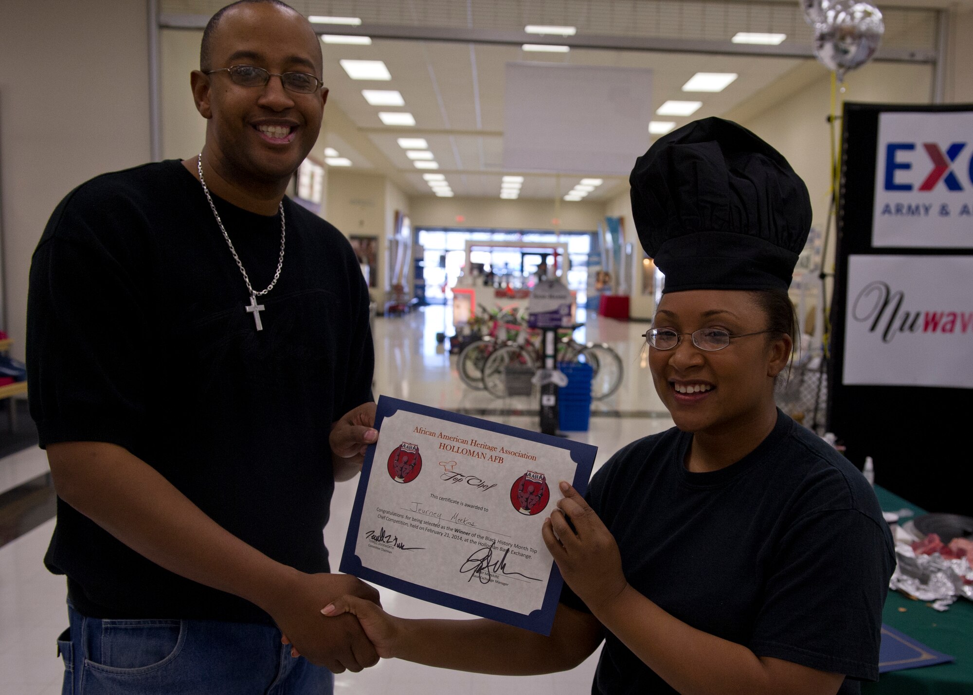 Handan Dvorak and Maj. Jeurney Meekins, 849th Air Maintenance Squadron commander, both finalists in the Holloman Top Chef competition, take a moment to pose while preparing their tables for the competition in the Holloman Air Force Base, N.M., Base Exchange Feb. 21. This was the first ever annual Holloman Top Chef competition held by the base’s African American Heritage committee. (U.S. Air Force photo by Airman 1st Class Chase Cannon/Released)