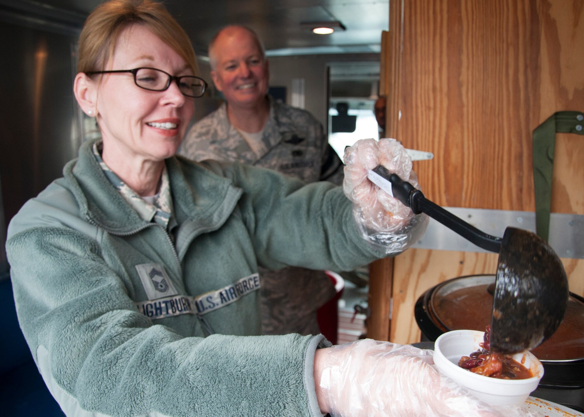 Chief Master Sgt. Janet Lightburn, 436th Airlift Wing Chiefs Group, ladles chili Feb. 19, 2014, Dover Air Force Base, Del. The chili provided Airmen on the flight line a small cup of something hot to help keep them warm on the cold rainy day. (U.S. Air Force photo/ Senior Airman Jared Duhon)