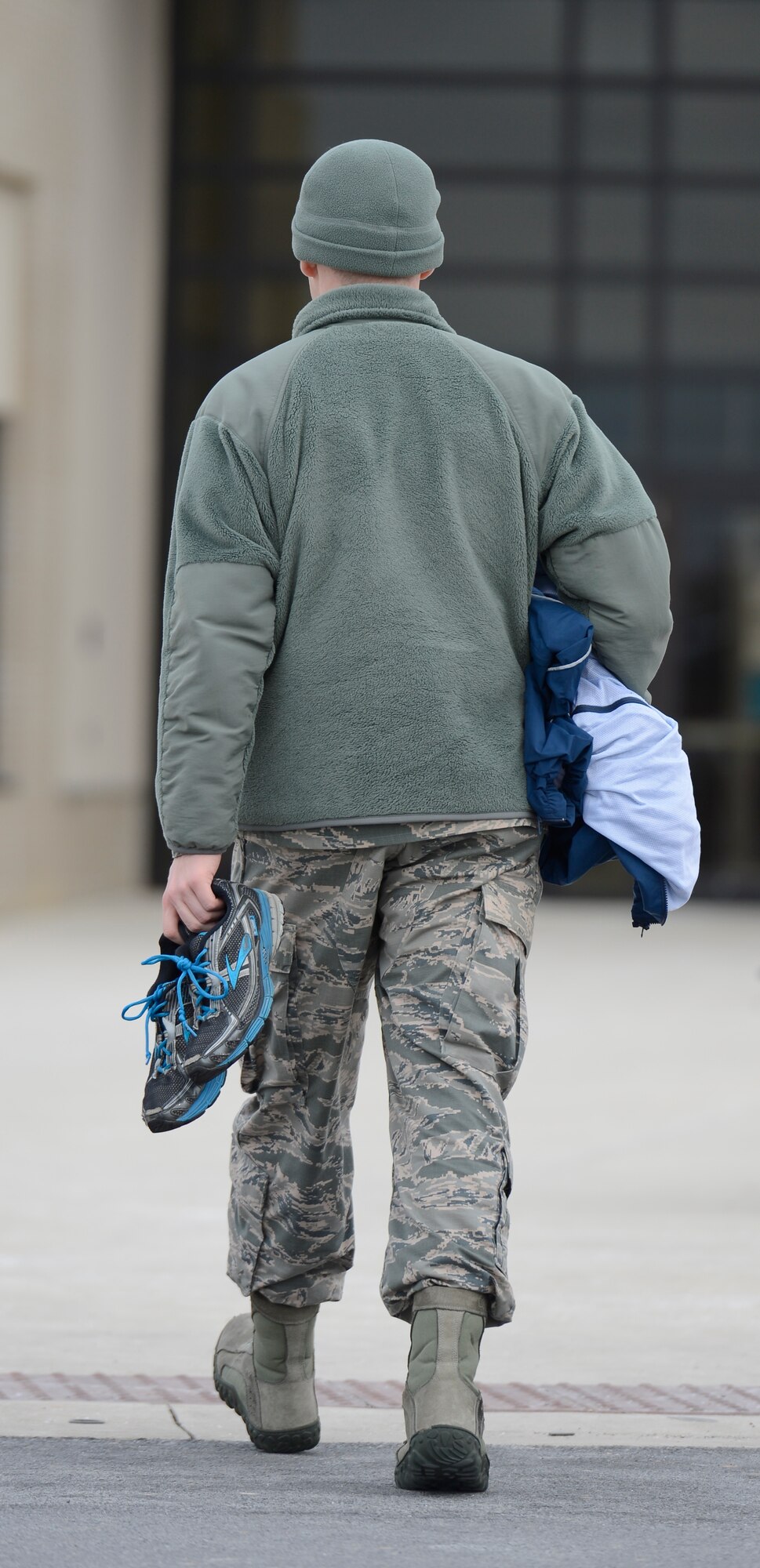 Airman 1st Class David Scott-Gaughan, a broadcaster with the 436th Airlift Wing Public Affairs Office, carries his clean athletic shoes and work out clothes in to the Dover Air Force Base fitness center on Feb. 12, 2014. The center has a two-shoe policy which mandates work boots or shoes cannot be worn in the facility to prevent dirt and salt from being tracked on to the fitness equipment and athletic courts. (U.S. Air Force photo/Greg L. Davis)  