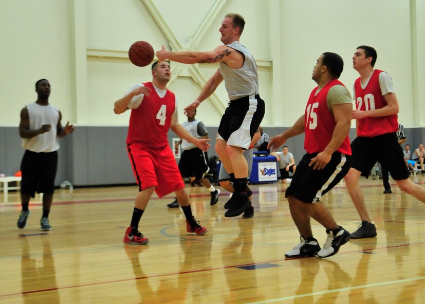 Lucas Evans, 436th Aerial Port Squadron guard, passes the ball around a 373d Training Squadron/Maintenance Operations Squadron player during an intramural basketball game Feb. 20, 2014, at the fitness center on Dover Air Force Base, Del. The 436th APS rallied back from six point deficit at half-time to win 76-68. (U.S. Air Force photo/Airman 1st Class William Johnson)