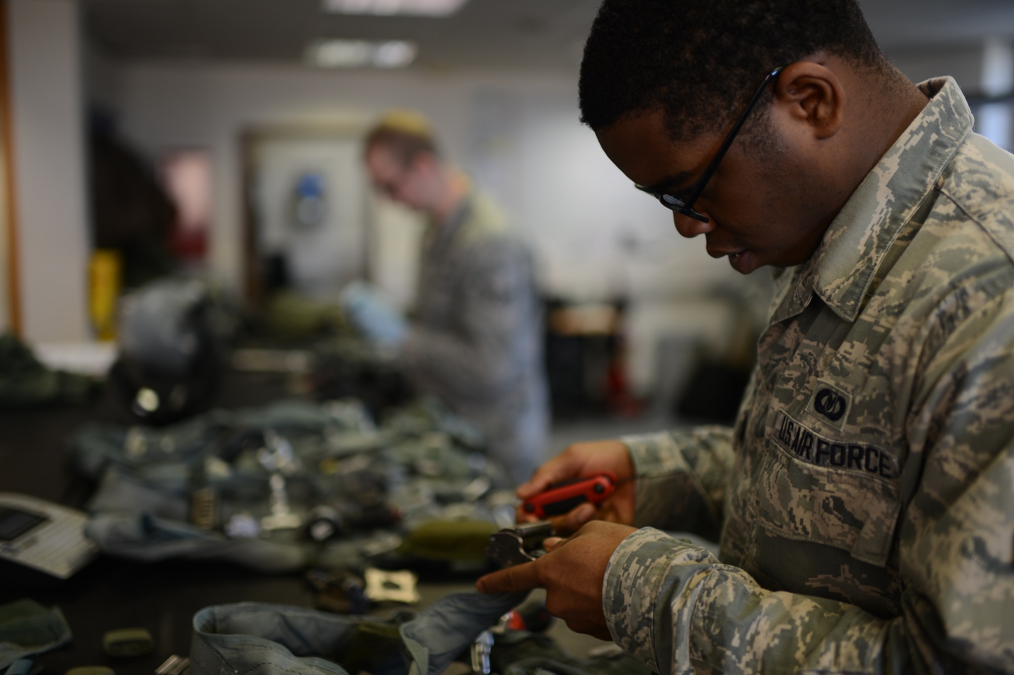 U.S. Air Force Airman 1st Class Stefon Newton, 52nd Operations Support Squadron aircrew flight equipment technician from Shreveport, La., dismantles a restraint harness at Spangdahlem Air Base, Germany, Feb. 24, 2014. The harness connects the pilot to the parachute and survival kit for use in case of in-flight emergencies and must be serviced every 30 days. (U.S. Air Force photo by Senior Airman Gustavo Castillo/Released) 