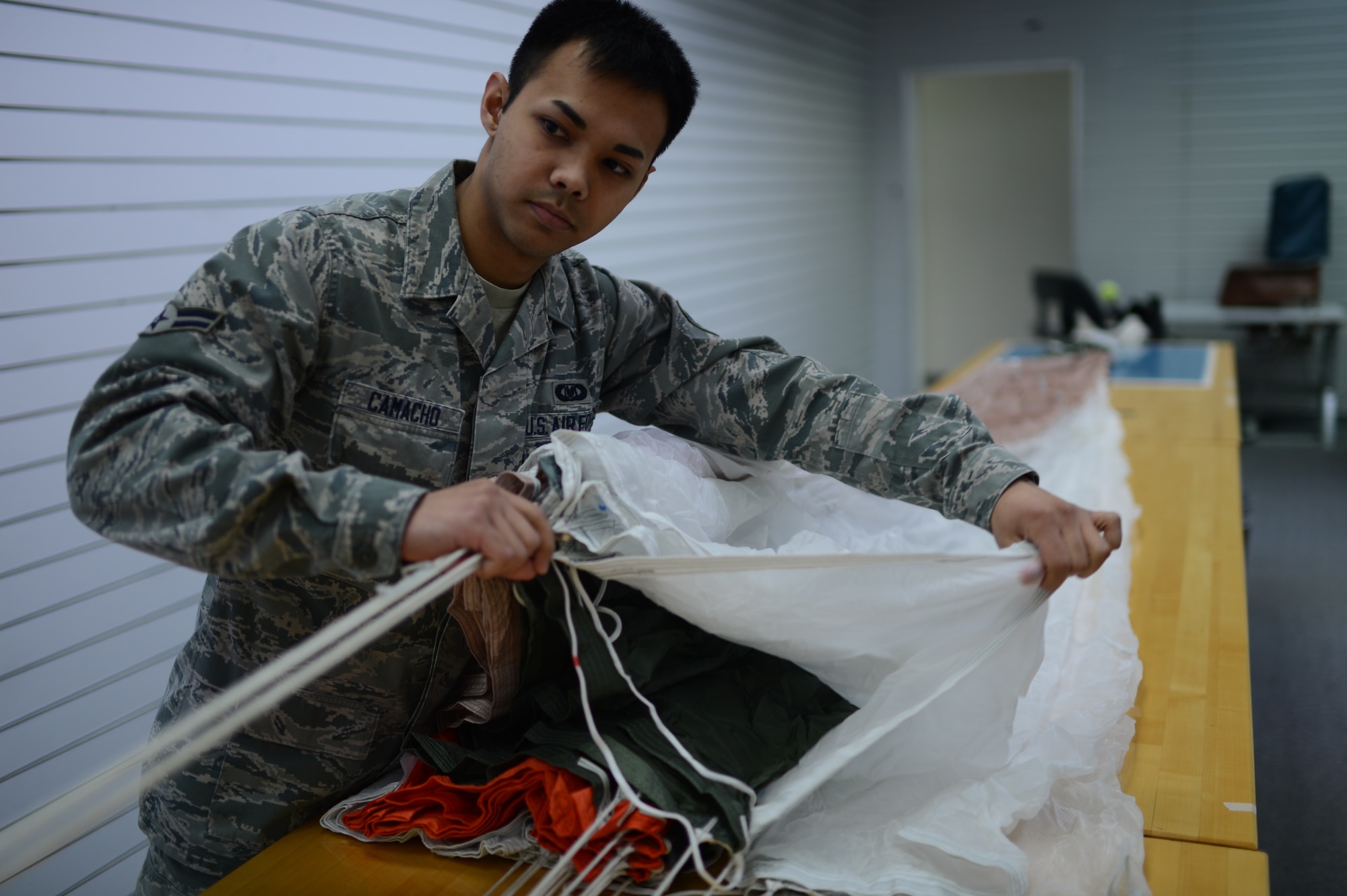 U.S. Air Force Airman 1st Class Timothy Camacho, 52nd Operations Support Squadron aircrew flight equipment technician from Guam, inspects a parachute at Spangdahlem Air Base, Germany, Feb. 24, 2014. Flight equipment technicians check parachutes for rips, tears and imperfections once a year. (U.S. Air Force photo by Senior Airman Gustavo Castillo/Released)