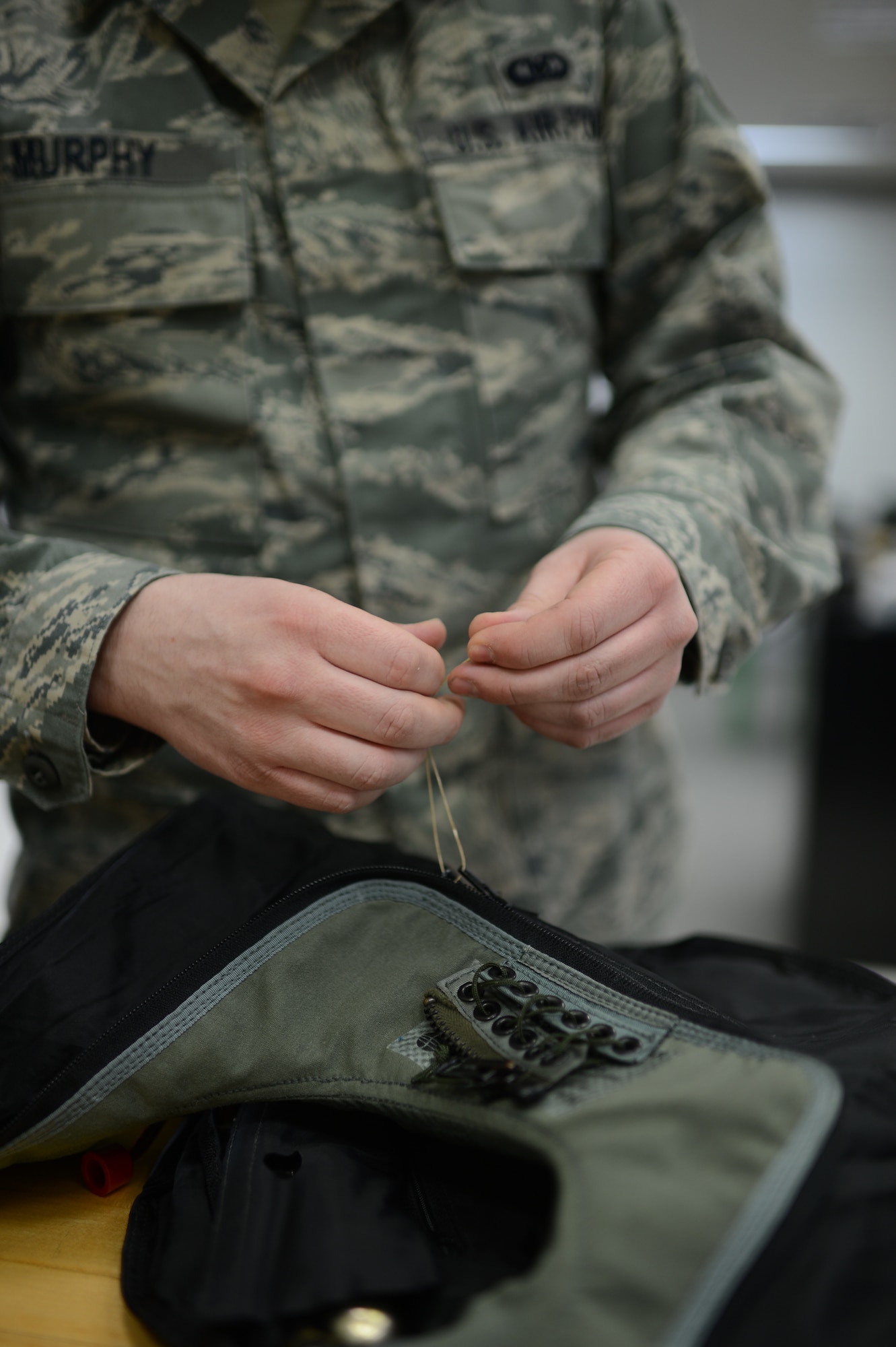 U.S. Air Force Airman 1st Class Remington Murphy, 52nd Operations Support Squadron aircrew flight equipment technician from Richland, Wash., ties a zipper of a life preserver unit at Spangdahlem Air Base, Germany, Feb. 24, 2014. The life preserver, which rests around a pilot’s neck, deploys on contact with water to ensure the user stays afloat after a crash. (U.S. Air Force photo by Senior Airman Gustavo Castillo/Released)