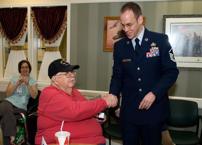 Master Sgt. Dallas Powers, 736th Aircraft Maintenance Squadron C-17 section chief, shakes hands with John Kroening, U.S. Army Air Force veteran, during a five year recognition event Feb. 19, 2014, at the Delaware Veterans Home (DVH) in Milford, Del. Powers, a Dover Air Force Base Top 3 member, presented Kroening with a commemorative pin to honor him for calling the DVH his home for five-plus years. (U.S. Air Force photo/Airman 1st Class Zachary Cacicia)
