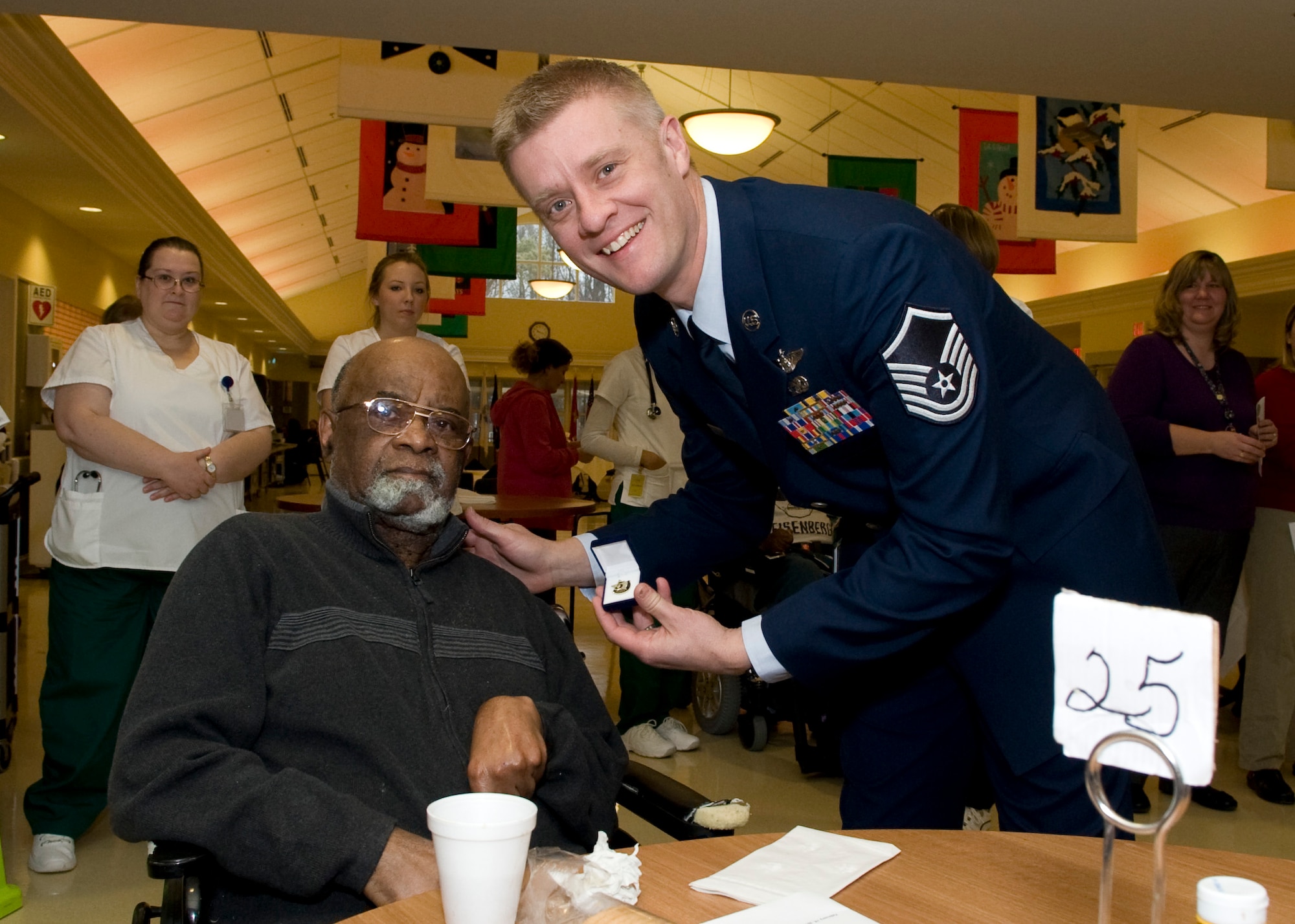 Master Sgt. Robert McGriffin, 9th Airlift Squadron loadmaster, presents Oakley Potts, U.S. Air Force veteran, with a commemorative pin at a five year recognition event Feb. 19, 2014, at the Delaware Veterans Home (DVH) in Milford, Del. McGriffin, Dover Air Force Base Top 3 president, led a group of Top 3 members to the DVH to honor those residents who have called it their home for five-plus years. (U.S. Air Force photo/Airman 1st Class Zachary Cacicia)