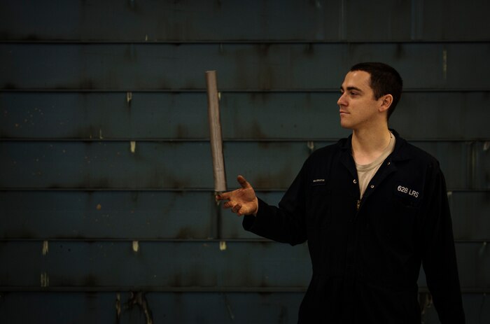 Senior Airman Benjamin Kingston, 628th Logistics Readiness Squadron vehicle maintainer journeyman, balances a pipe on his finger as he heads to his next vehicle inspection job Feb. 11, 2014, at Joint Base Charleston, S.C. Vehicle maintainers take time to relax in between jobs, because it can be stressful working on the various vehicles that come through the shop. (U.S. Air Force photo/ Senior Airman Dennis Sloan)