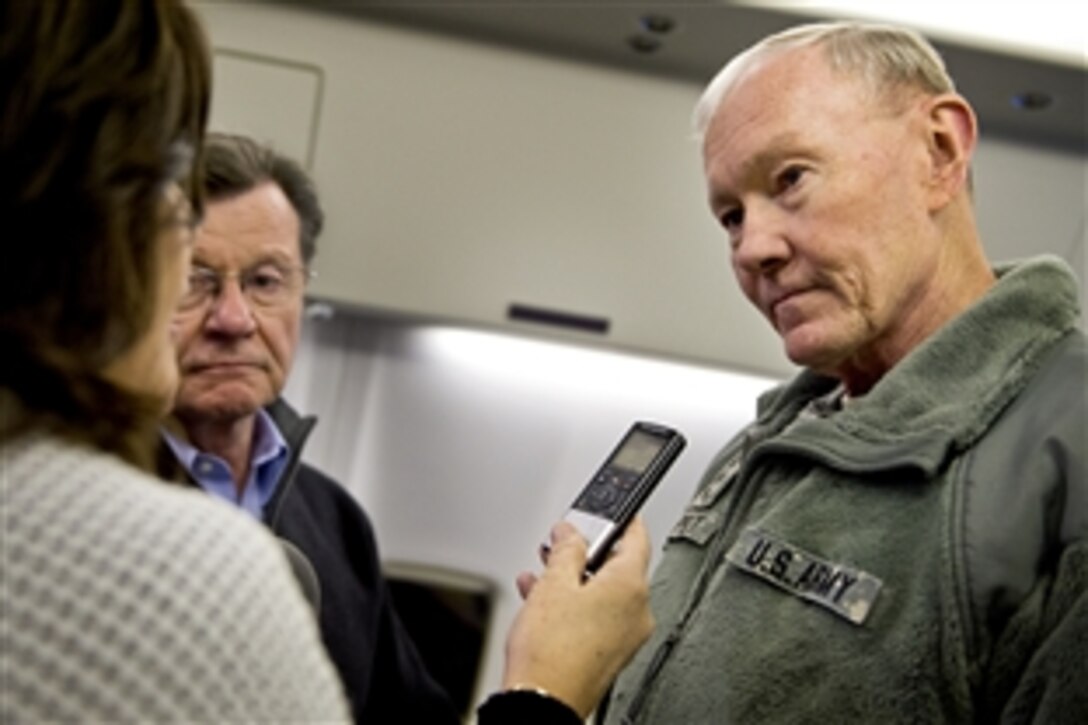 U.S. Army Gen. Martin E. Dempsey, chairman of the Joint Chiefs of Staff, listens to a question from Lolita Baldor, Associated Press Pentagon reporter, while flying on a U.S. military aircraft en route to Afghanistan, Feb. 24, 2014.