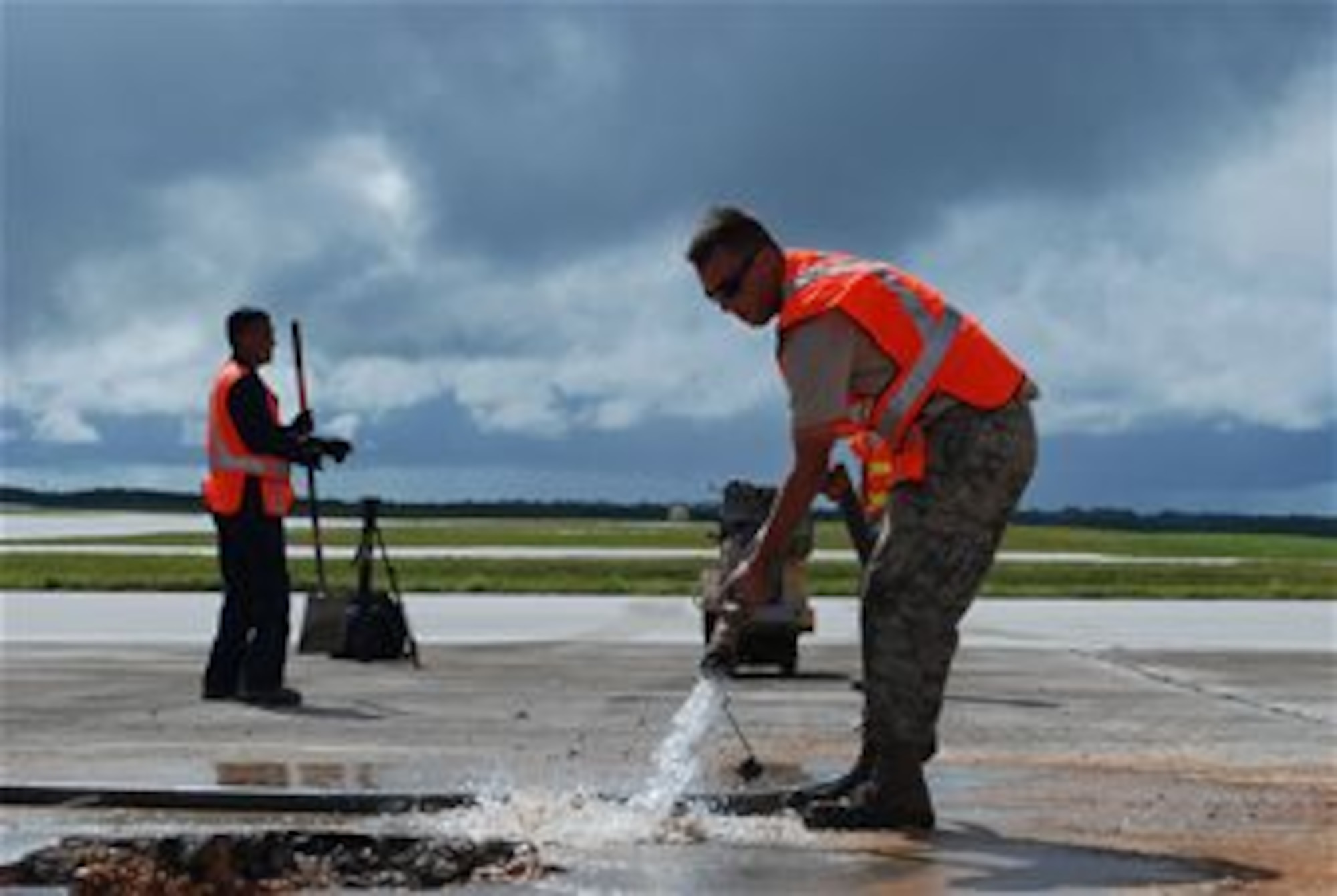 Staff Sgt. Austin Winegardner, 36th Civil Engineer Squadron project leader, pours water on the cuts around the simulated damaged area created during an airfield damage repair training exercise on the Andersen Air Force Base, Guam flightline Jan. 23, 2014. The 36th Civil Engineer Squadron Airmen were the first in the Air Force to receive training on a new airfield damage repair capability. (U.S. Air Force photo by Airman 1st Class Emily A. Bradley/Released)