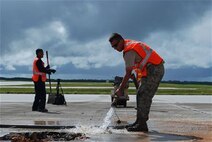 Staff Sgt. Austin Winegardner, 36th Civil Engineer Squadron project leader, pours water on the cuts around the simulated damaged area created during an airfield damage repair training exercise on the Andersen Air Force Base, Guam flightline Jan. 23, 2014. The 36th Civil Engineer Squadron Airmen were the first in the Air Force to receive training on a new airfield damage repair capability. (U.S. Air Force photo by Airman 1st Class Emily A. Bradley/Released)